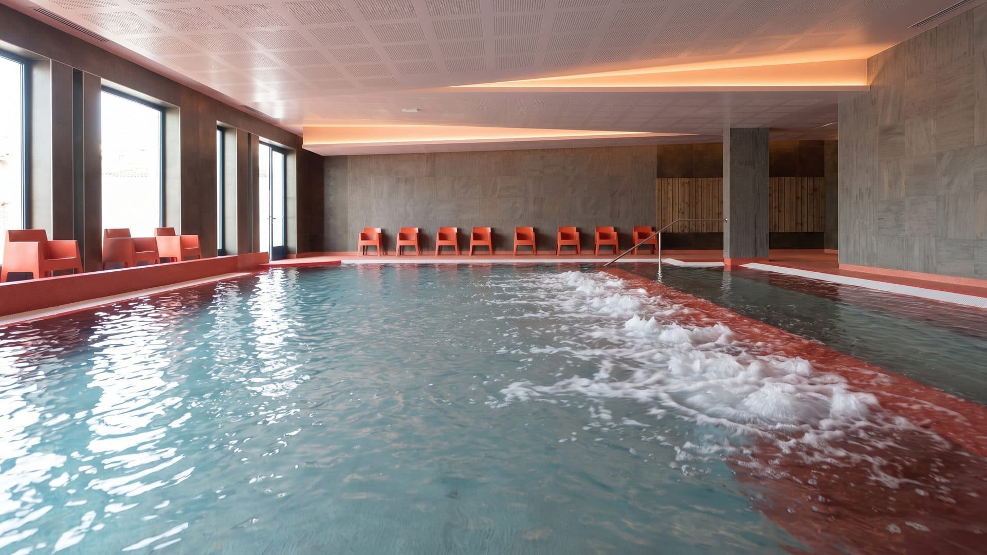 The thermal basin of the Aïga Resort with its bubbling jets along the orange loungers