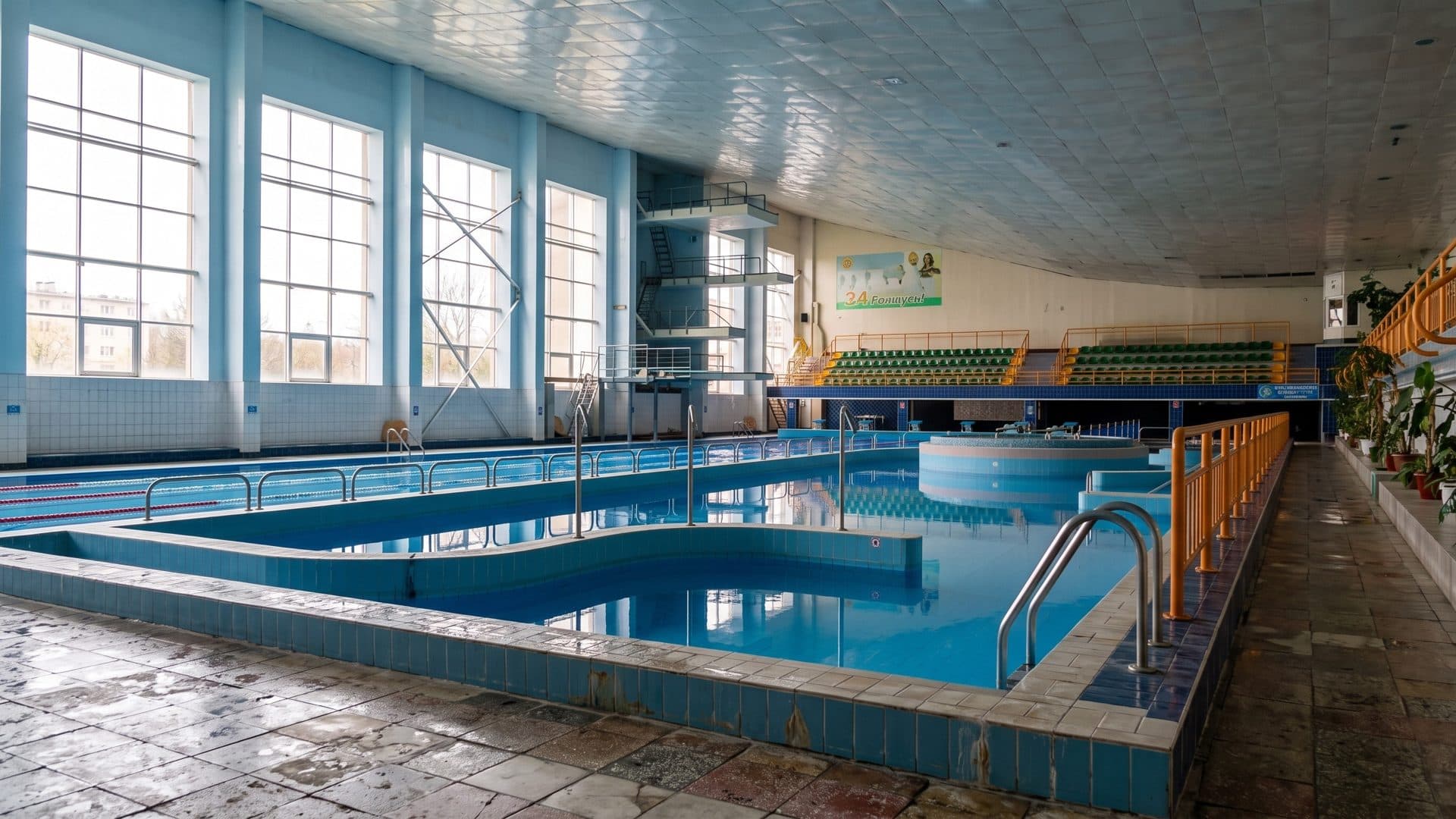 The indoor pool of the Aquacentre in Grodno with lanes and a whirlpool along a row of tall windows
