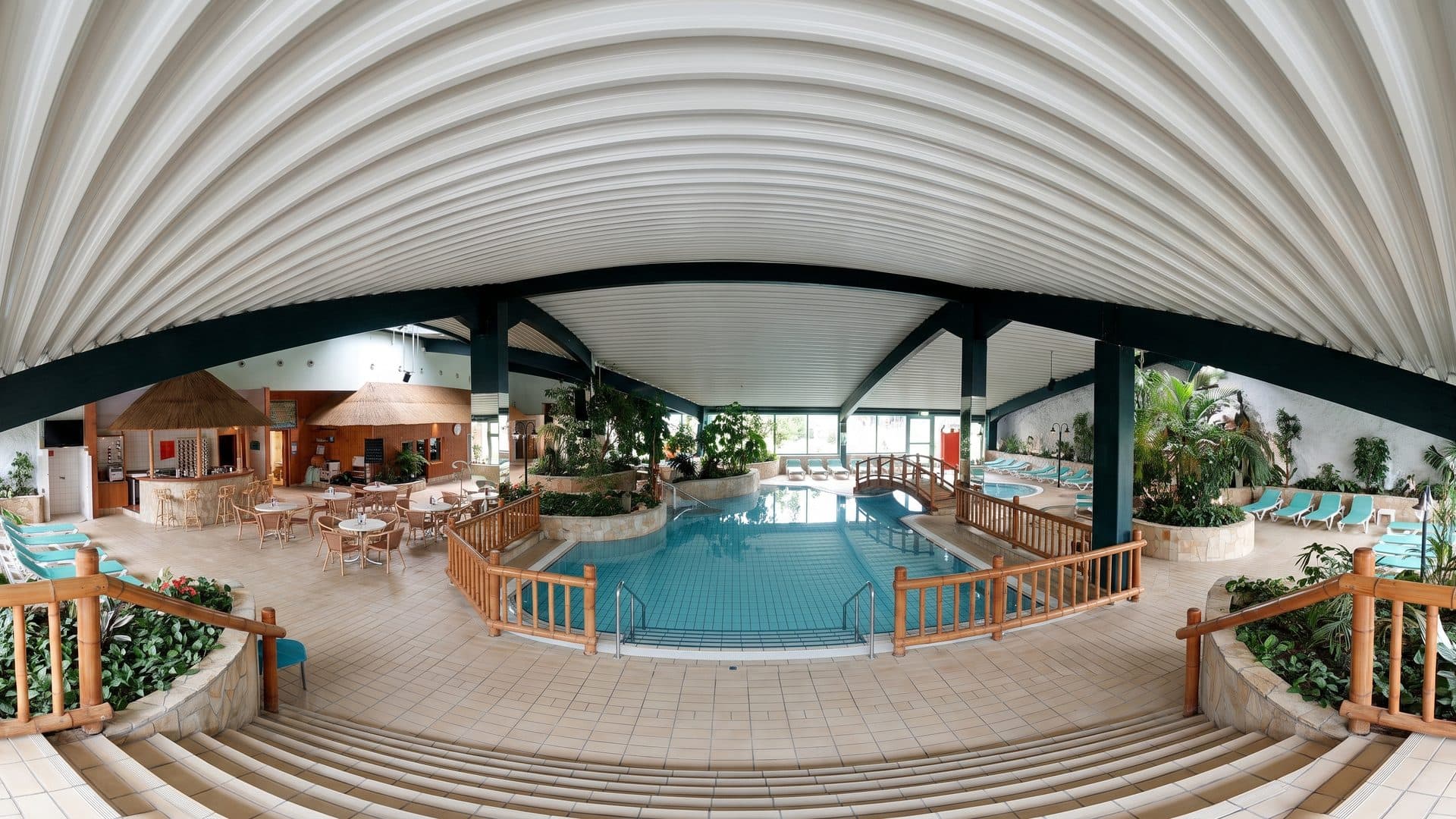 The pool of the Altmark-Oase under its white vaulted roof among the planting