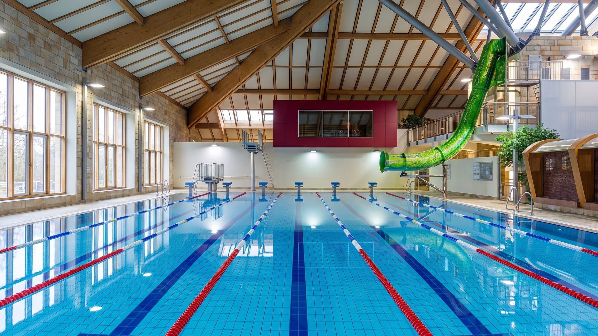 The indoor hall of AquaFun Soest with swimming lanes, a coloured slide and tall windows