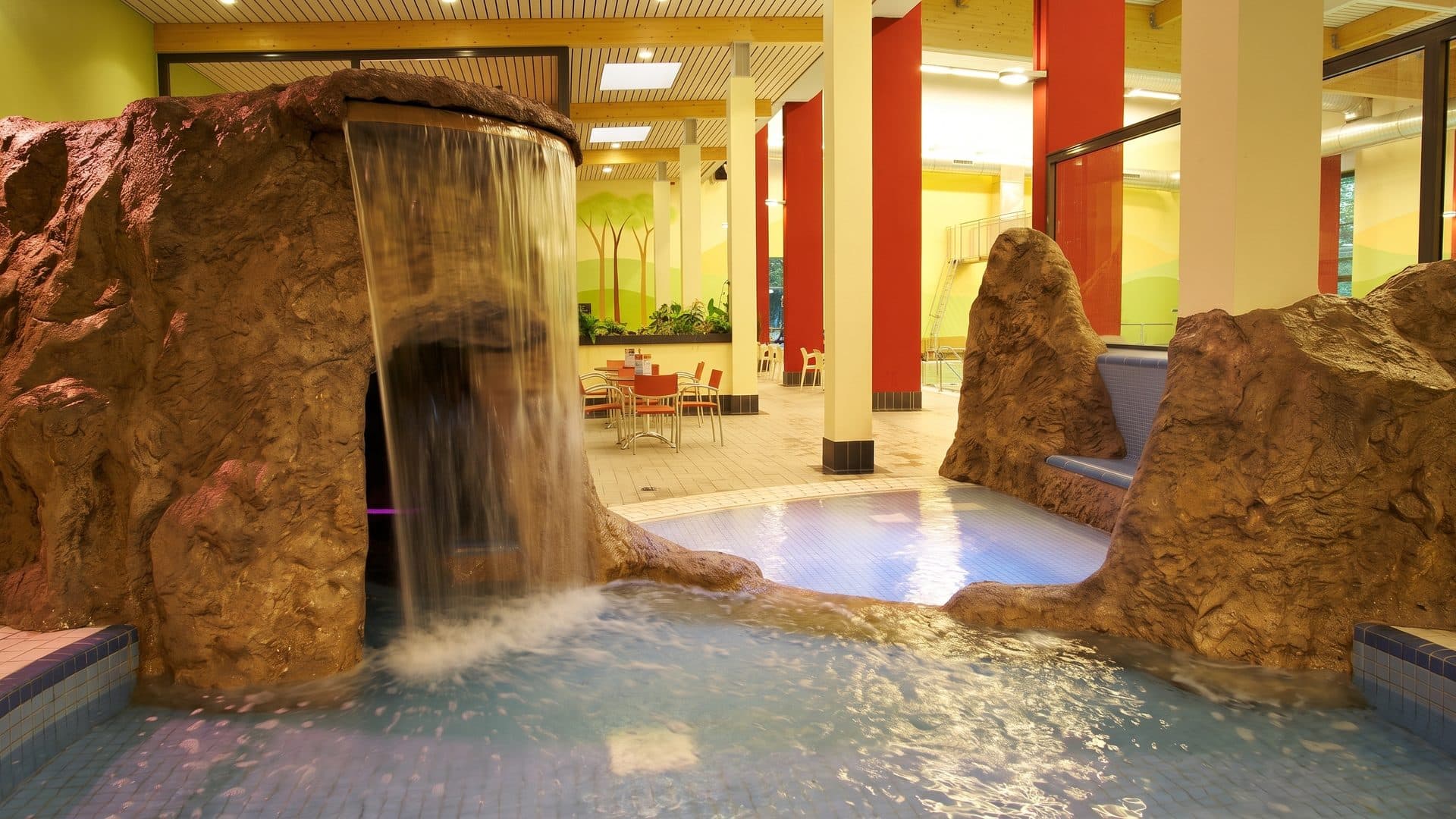 The rock grotto of Aqua Olsberg with its waterfall beside the warm-lit indoor pool