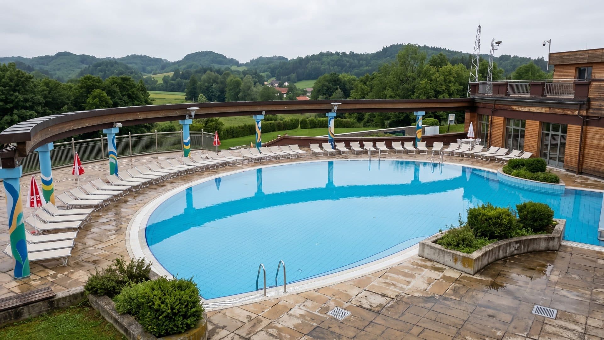 The large oval outdoor pool of Aquae Vivae in Krapinske Toplice under a curved canopy, green hills behind