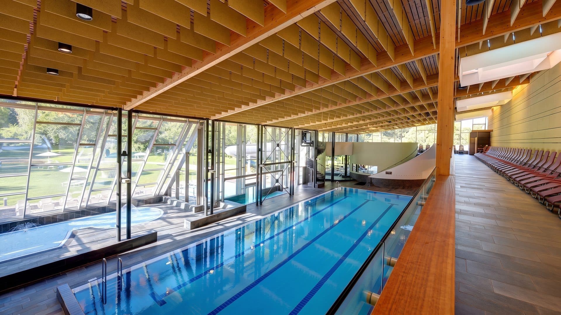 The pool of Aquaforum under its timber-ribbed roof beside the glazed wall