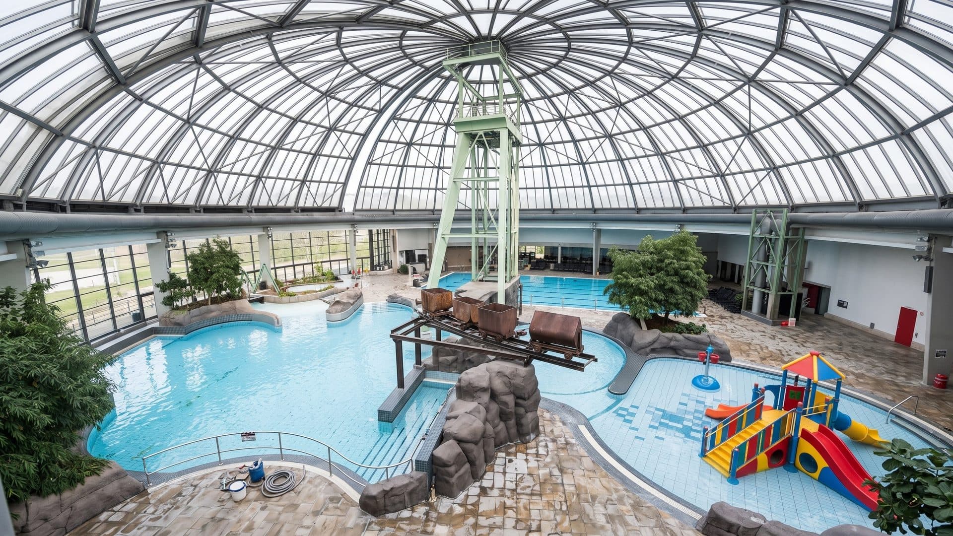 Pools of the Aquapark Oberhausen under a large glass dome with a mine headframe and a play tower