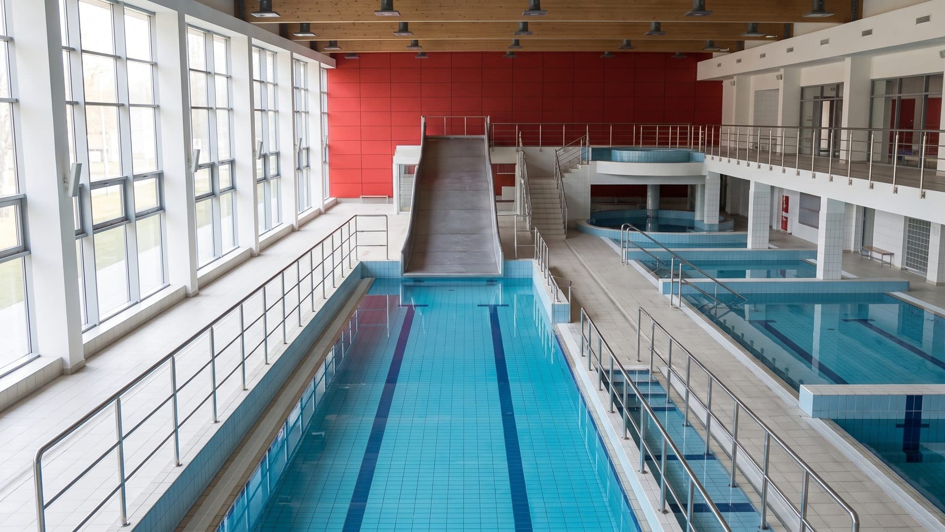 The stepped pools of the Suwałki water park below their grey slide and red wall