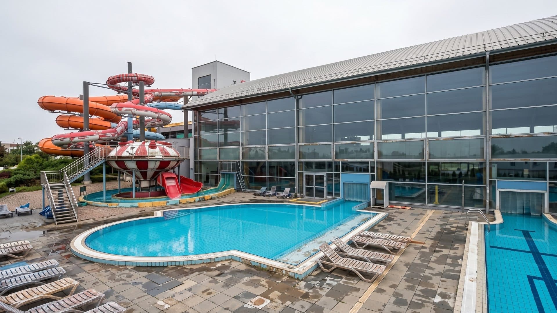 Outdoor pools of the Aquapark Wroclaw beside the glazed hall and a tower of red slides