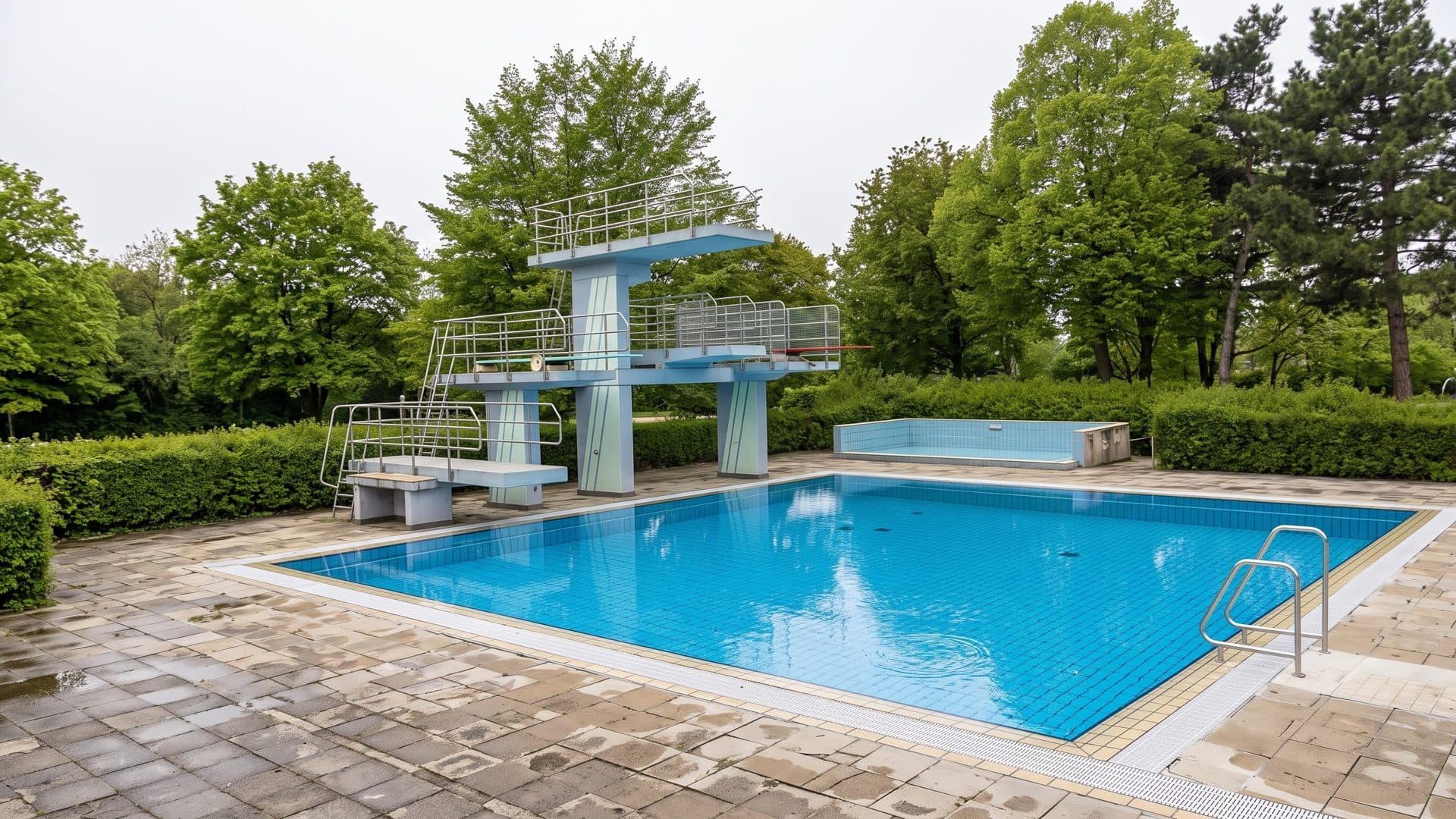 The outdoor diving pool of AquaSol Kempen with a concrete diving tower among trees