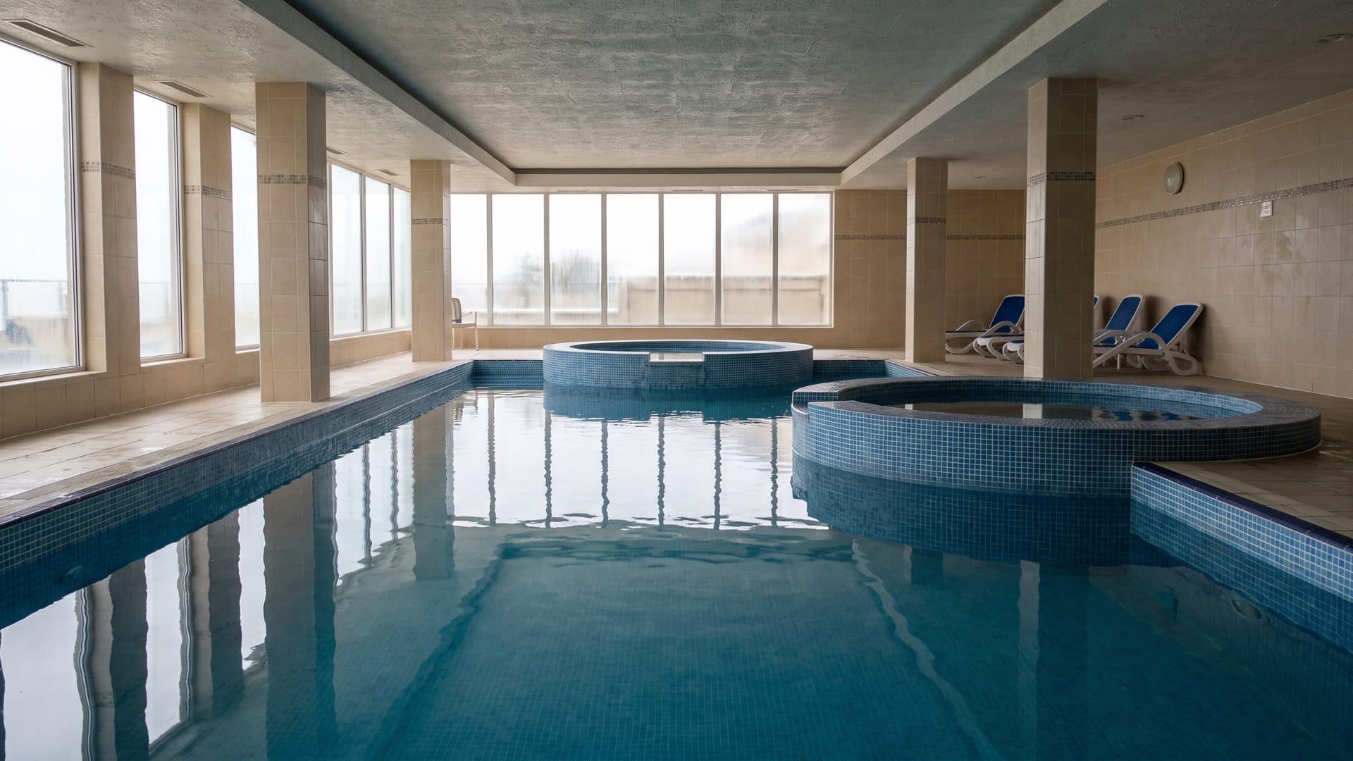 The mosaic-tiled indoor thermal pool and whirlpool basin at Aquatonik in Velingrad, lit by tall windows