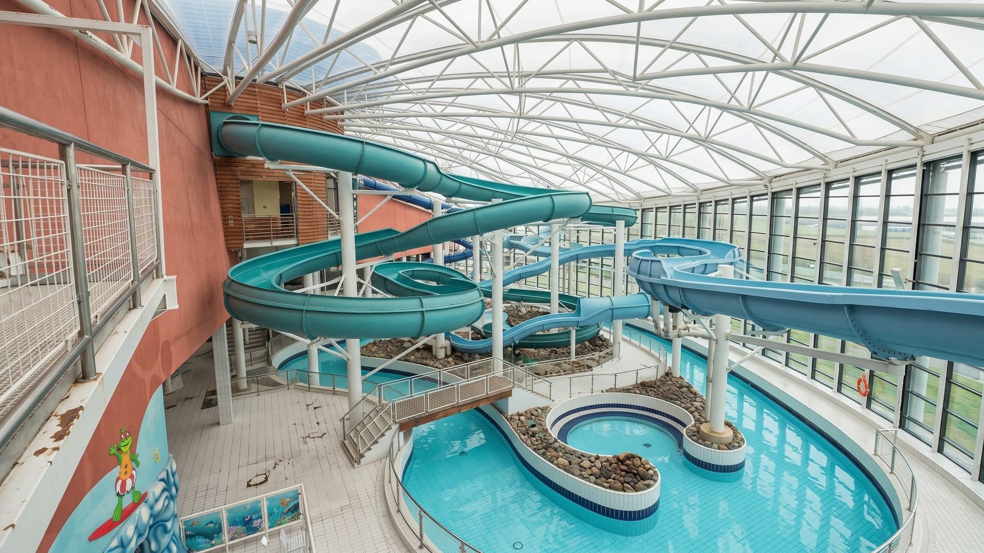 Green slides curving over the pools of the Aquazone in Dublin under a light steel roof