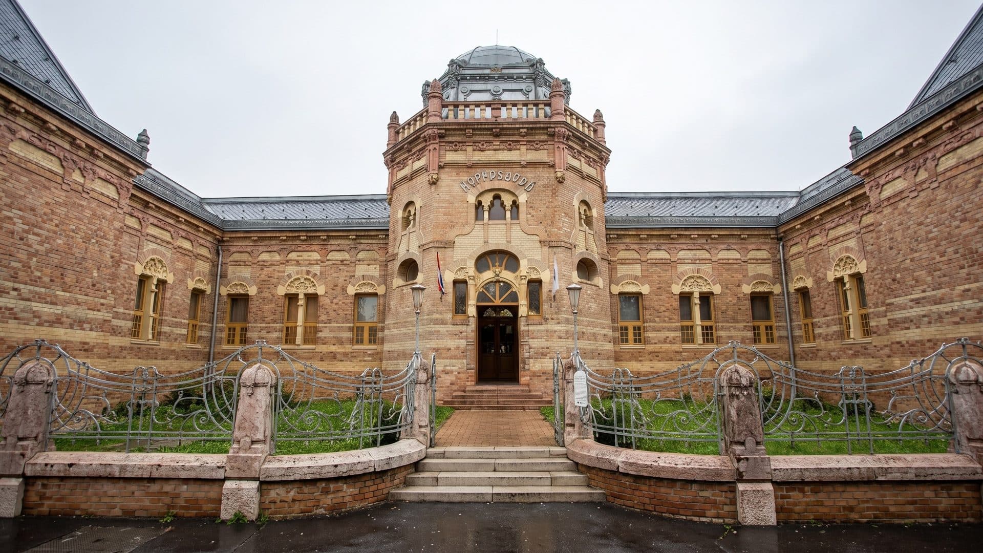 The brick bathhouse with its domed central tower and ornate entrance, seen across the front courtyard