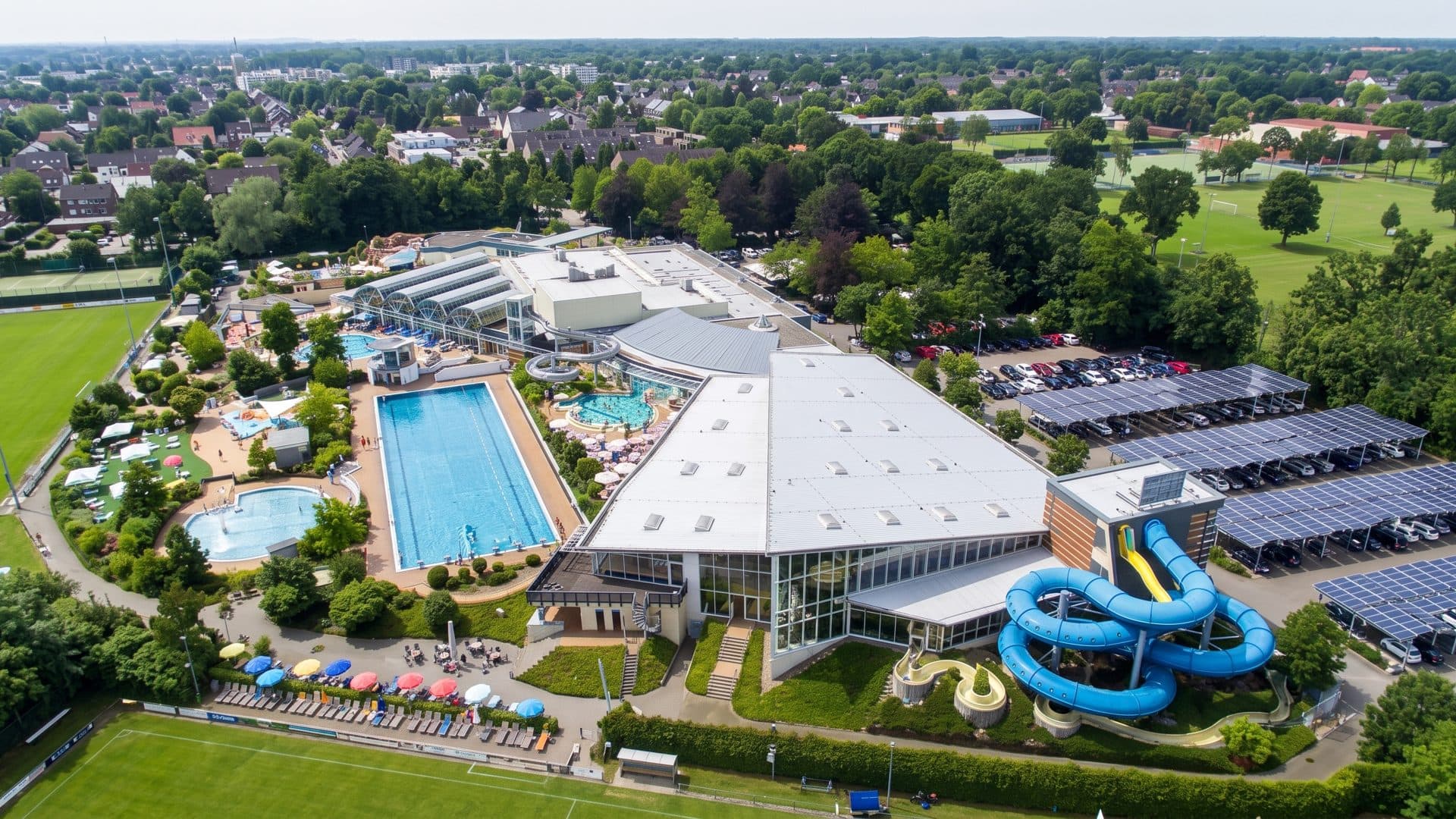 The baths from the air: the long hall, its outdoor swimming pool and the blue slide coiling beside it.