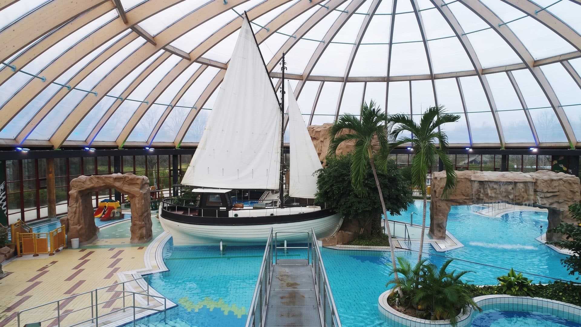 A sailing boat in the indoor leisure pool of Atlantis in Dorsten under a glass dome with palms