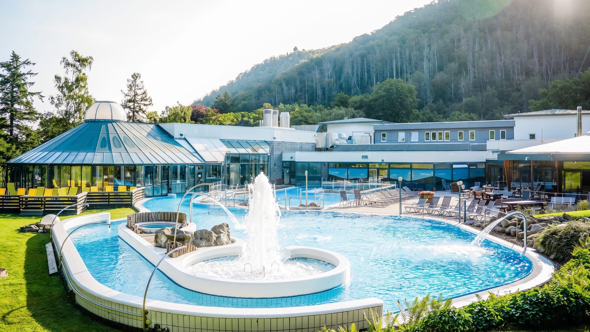 The outdoor brine pool at the Sole-Therme in Bad Harzburg, with a fountain and the wooded Harz slopes rising behind.