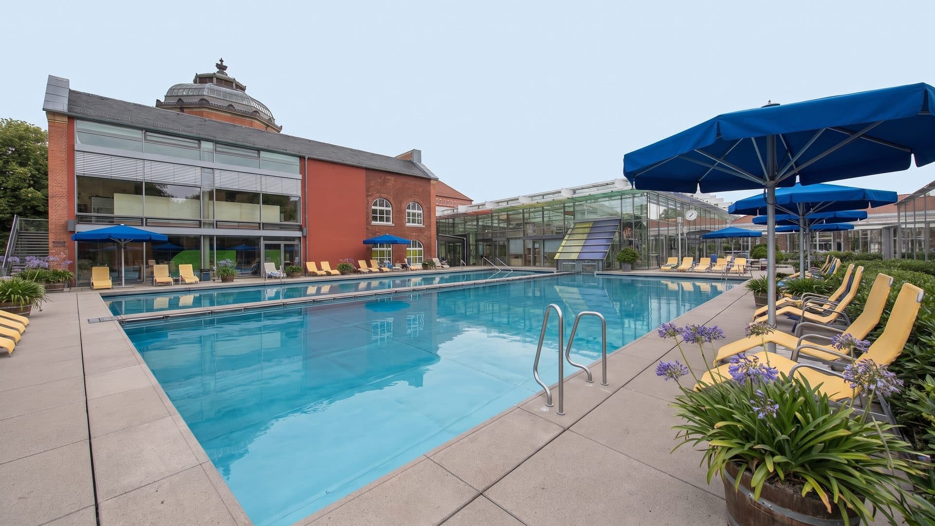 The outdoor pool of the historic Albert-Bad with parasols and loungers in front of the brick building
