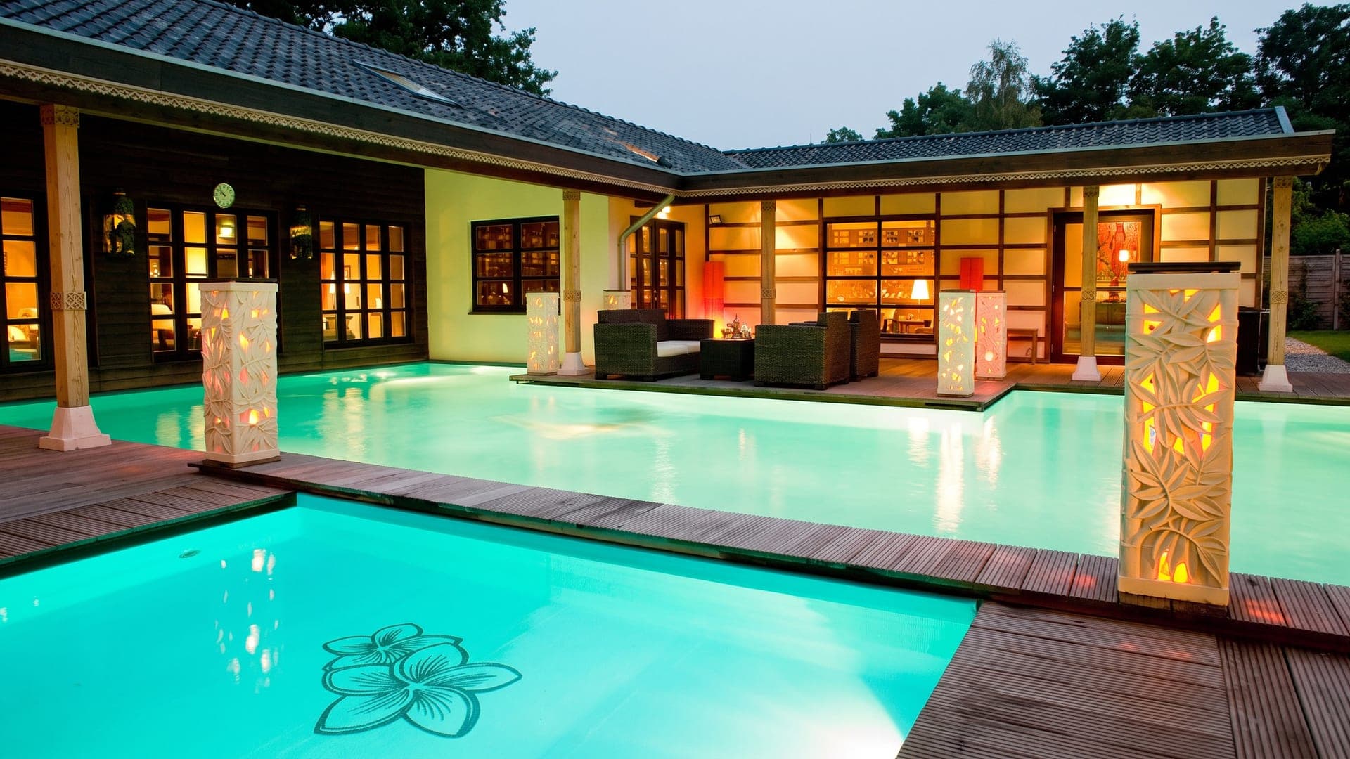 The same courtyard at night, lit by carved lanterns along the water