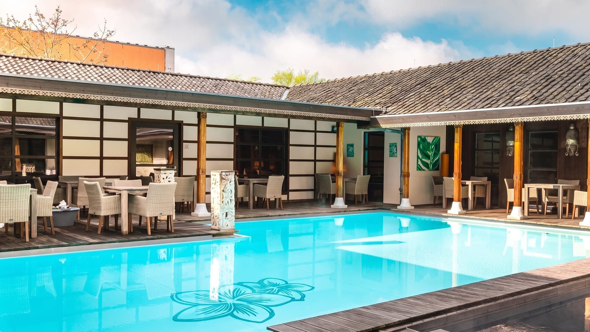 Balinese courtyard pool under tiled roofs, a flower motif on the pool floor