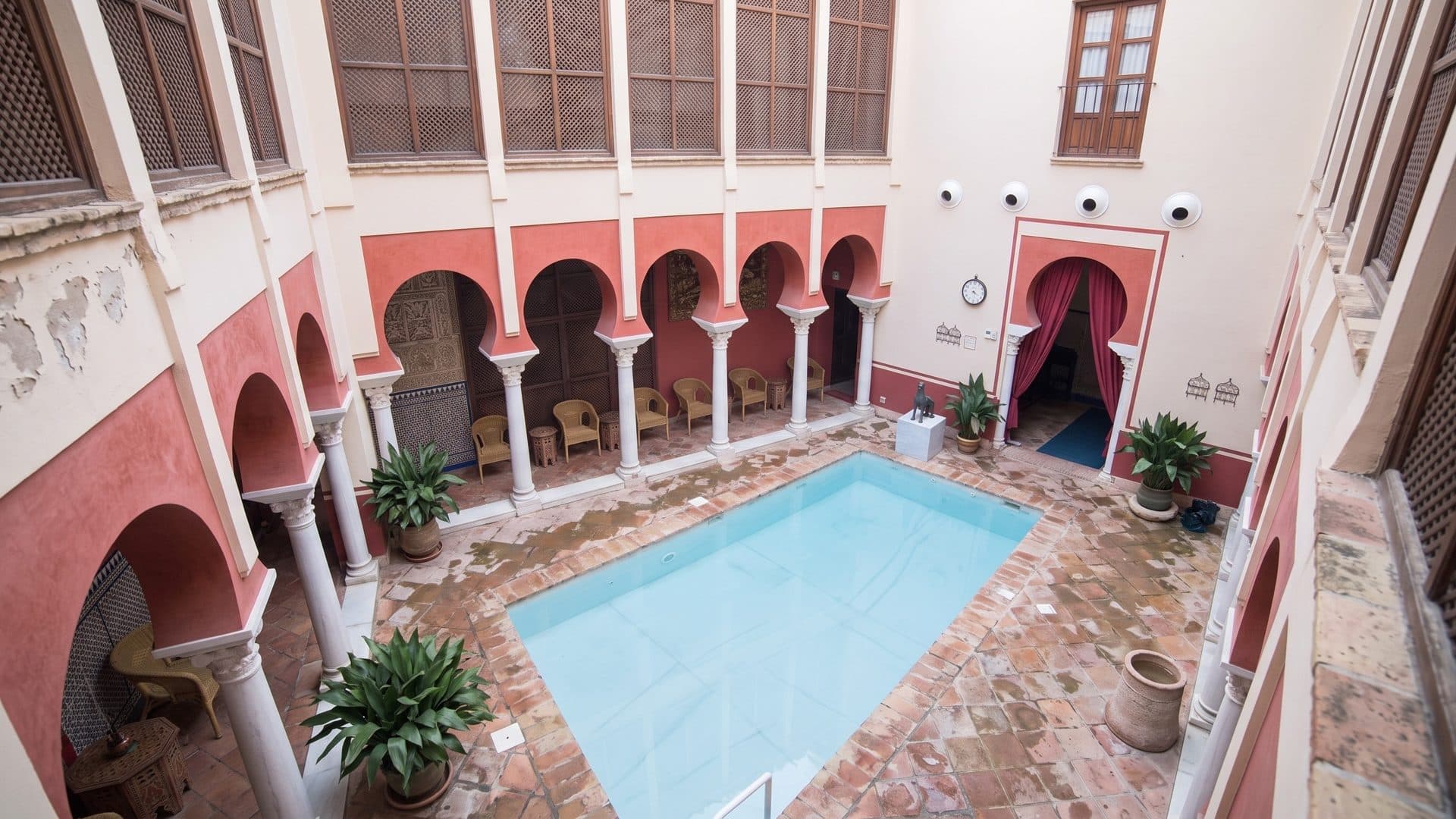 The pool of the Arab baths in Cordoba seen from above, framed by horseshoe arches in red and cream