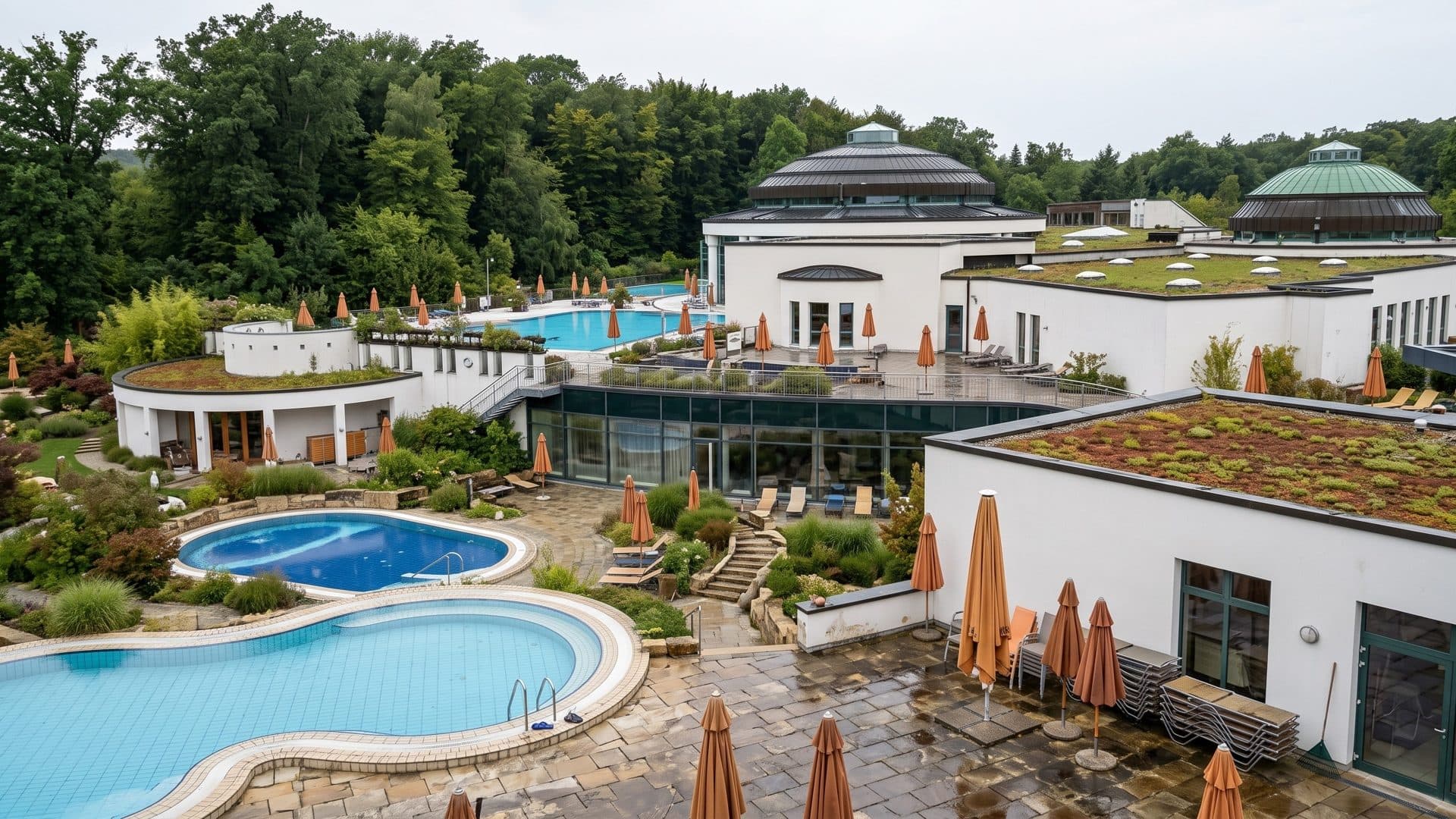 Curved outdoor pools of the Bentheimer Mineraltherme in a garden before the white domed pavilions