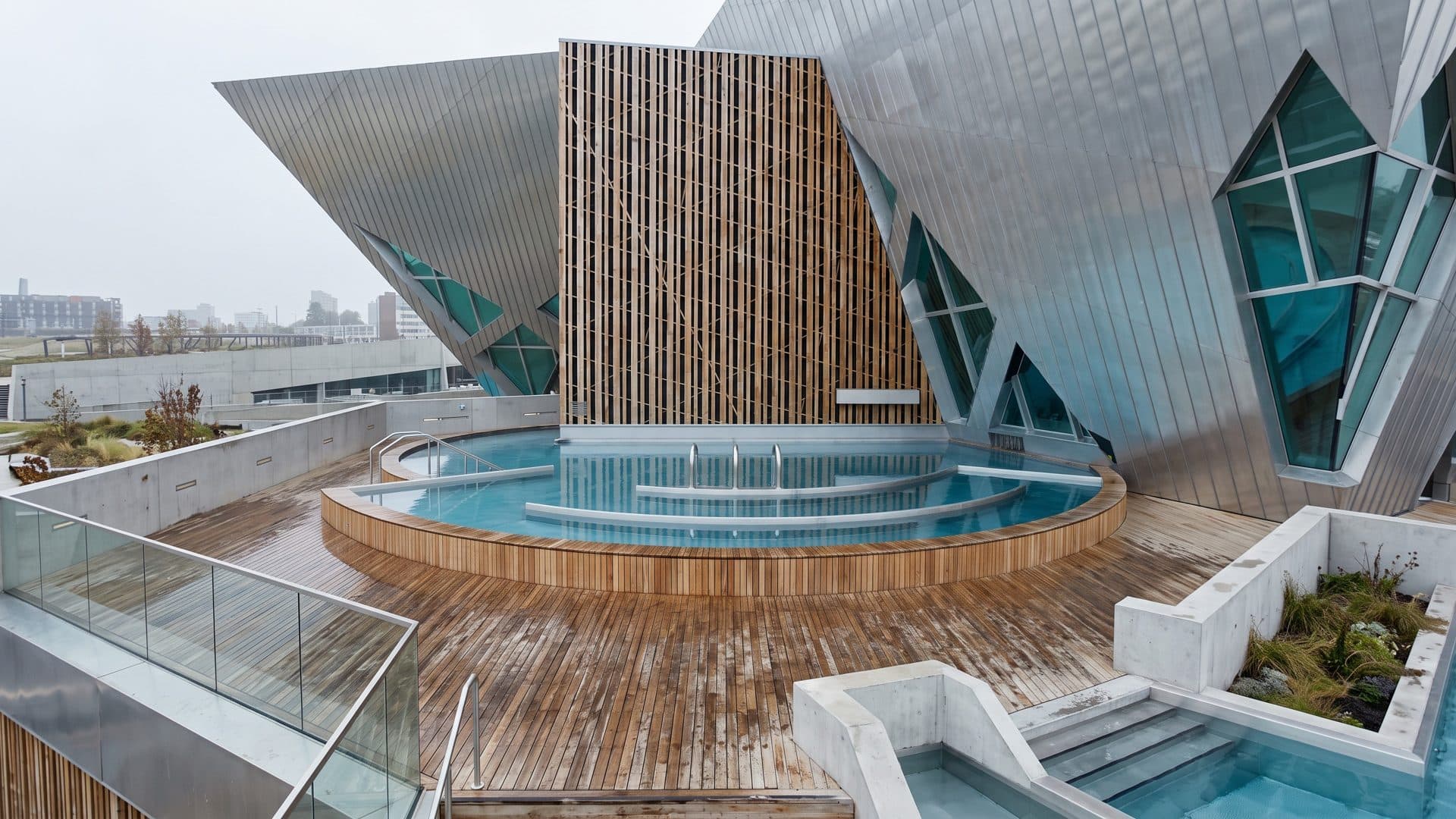 The round outdoor pool of Bernaqua below the angular metal and timber facade