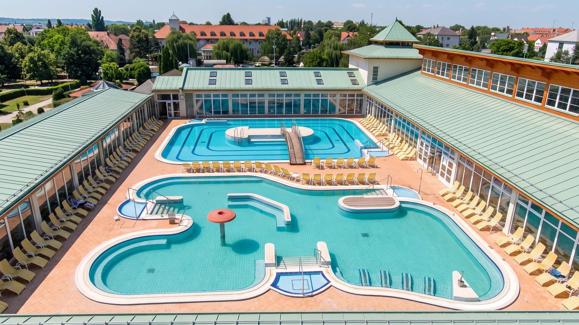 The Flexum thermal bath in Mosonmagyarovar seen from the air, its pool cluster ringed by the mint-green roofed building.