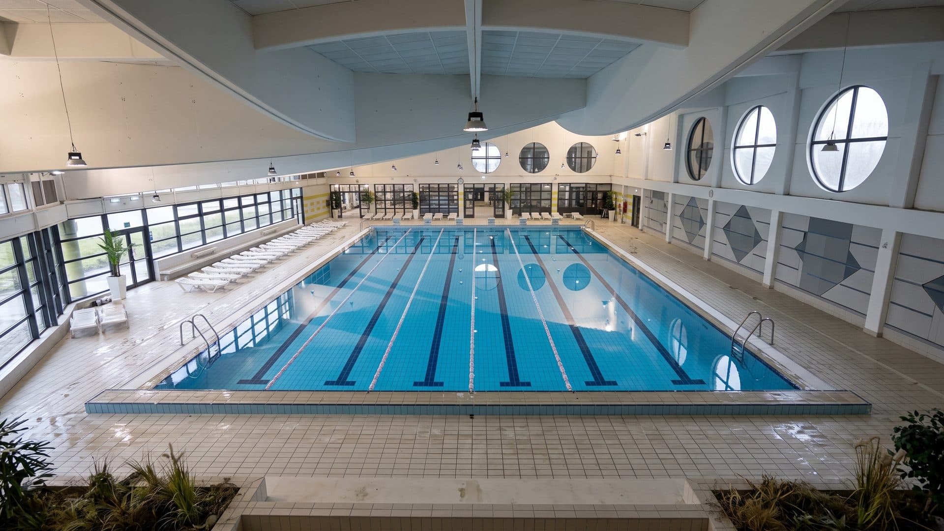 The indoor lane pool of Bizovacke Toplice in a white hall with round porthole windows
