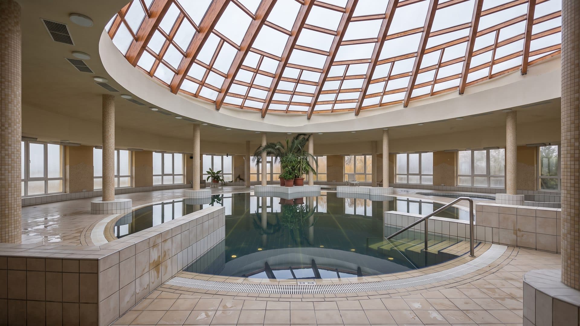 Thermal pool under a ribbed glass dome, with the gallery and columns of the round hall around it.