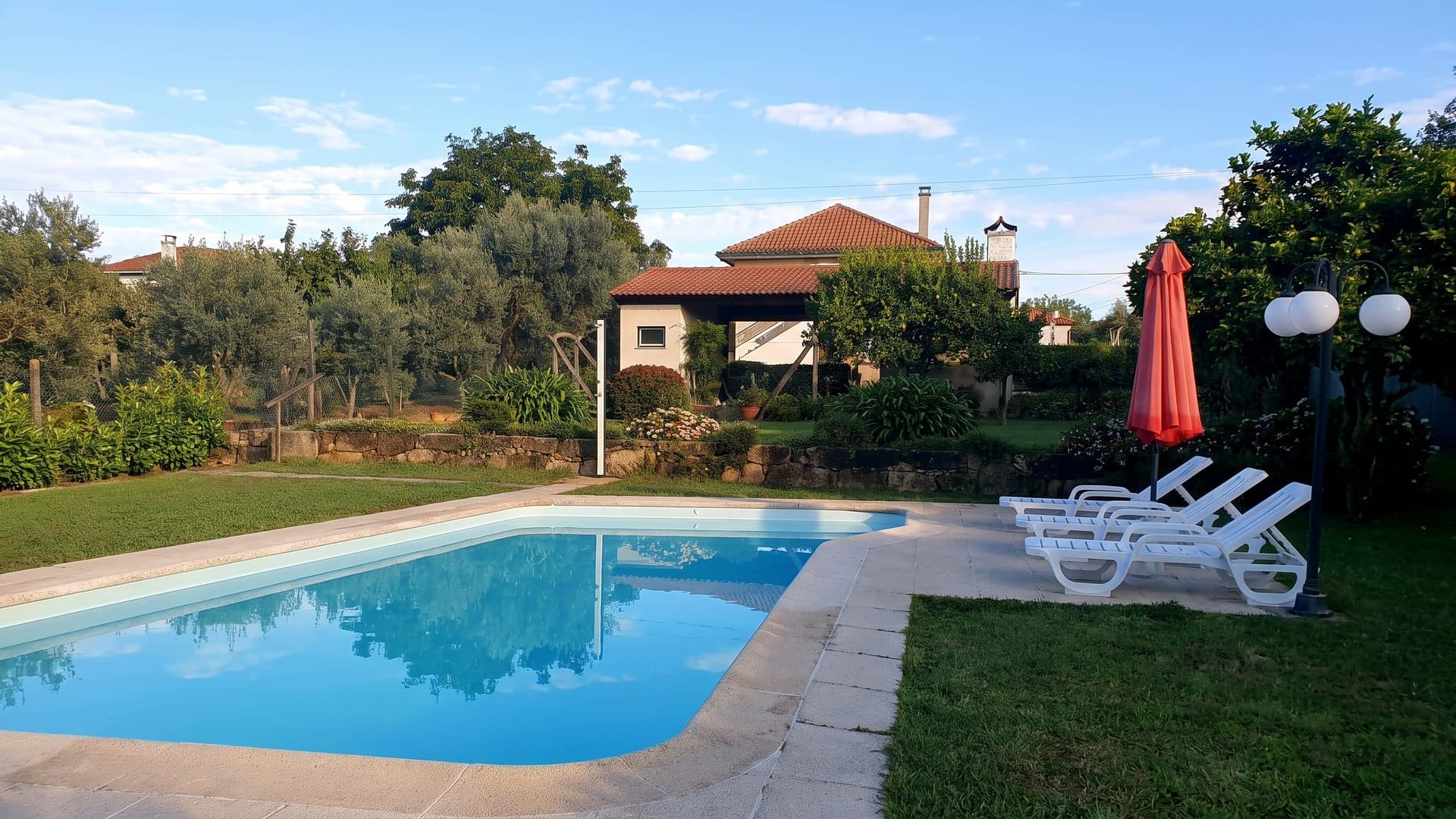The outdoor pool of Caldas de Sangemil with loungers along its side and the spa building behind