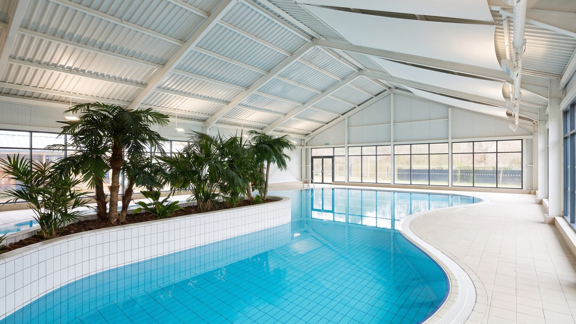 The pool of the Calluna around its planted island under the white ribbed roof