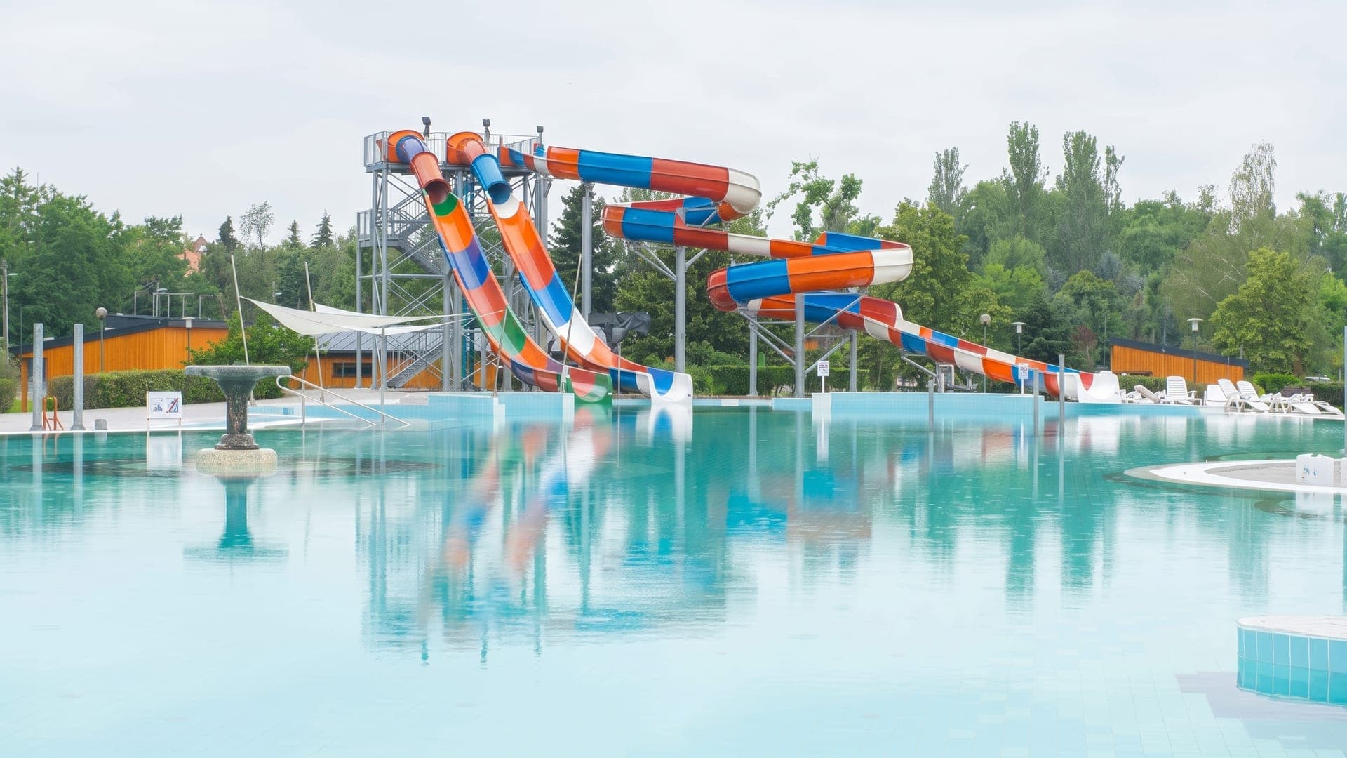 Outdoor pool with red, yellow and blue slides on a gravel apron