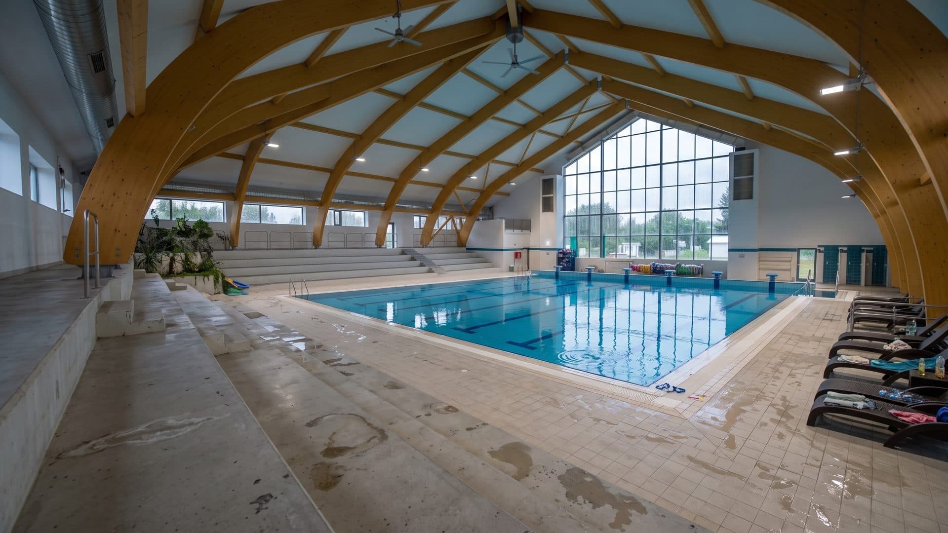 The lane pool of the Csurgo town baths under curved laminated timber arches and a tall glazed gable