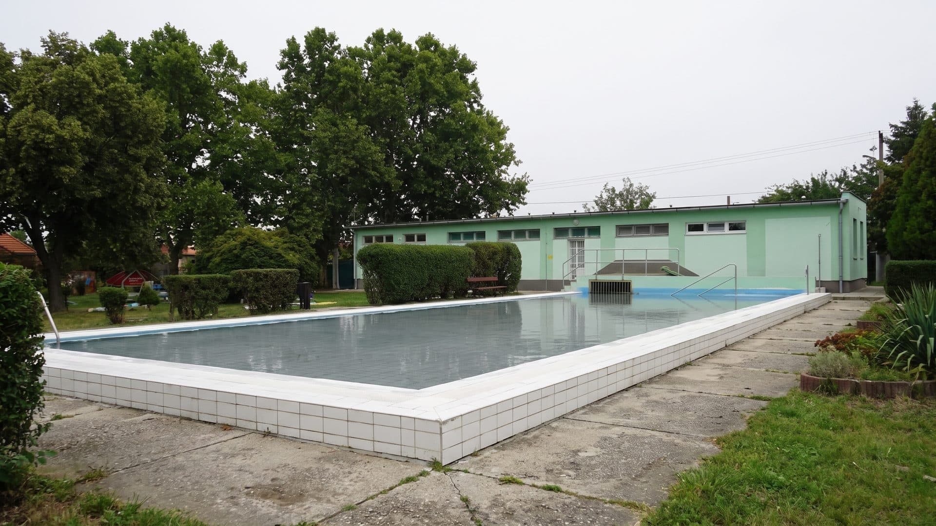 The outdoor pool at the Devavanya thermal bath beside its low green-painted bath building
