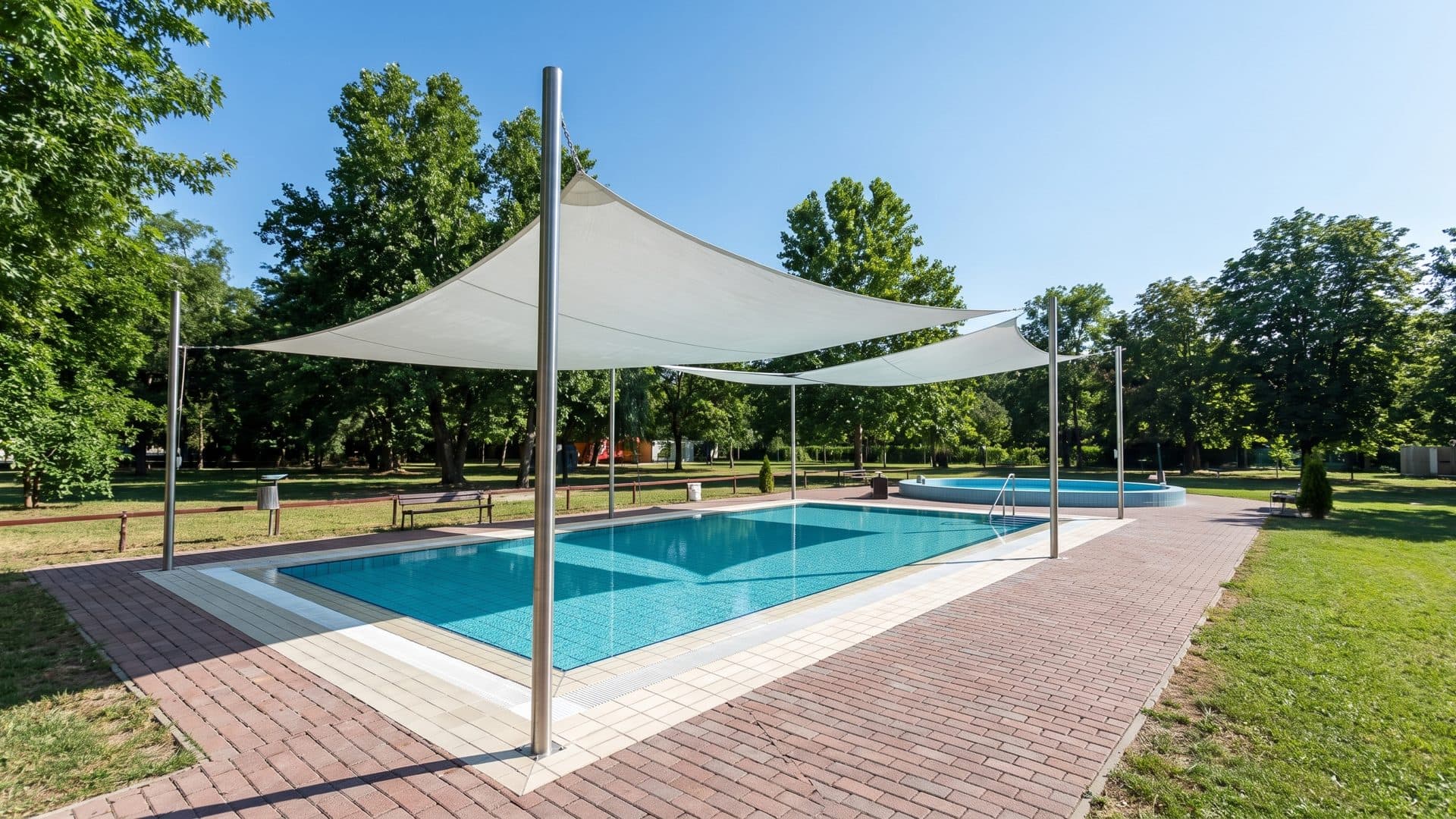 The outdoor pool of the Dunaföldvár baths under its white shade sails among the park trees