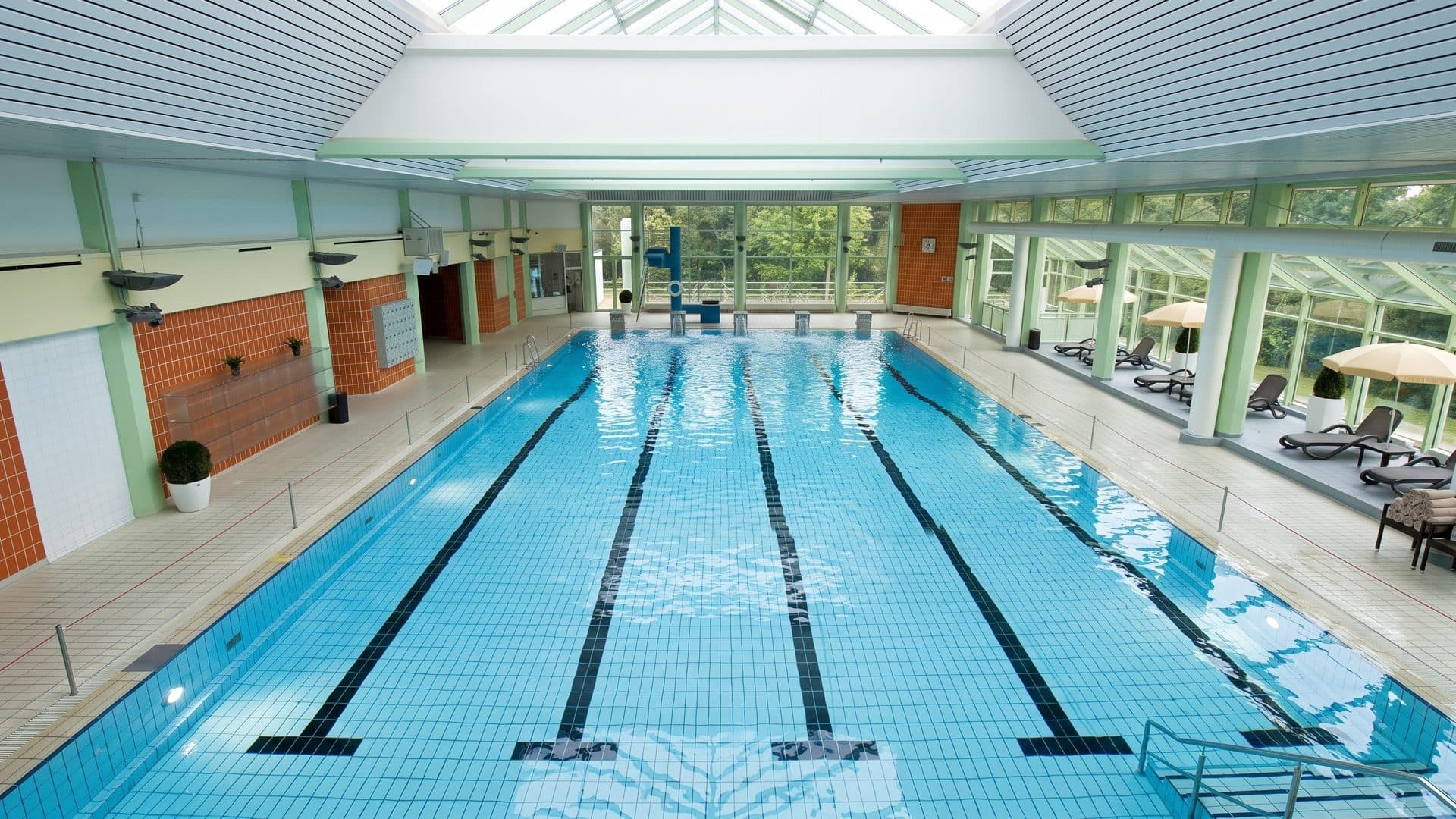 The lane pool of the Eau Le in Lemgo under a pale ribbed ceiling, orange tiled walls on one side and a glazed winter garden on the other
