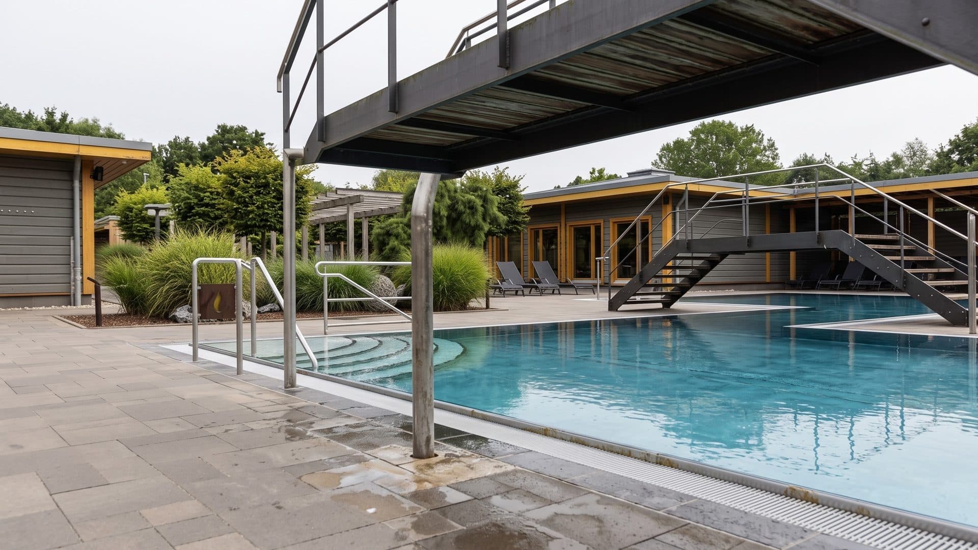 The outdoor pool of Embricana with a timber footbridge over the water and low timber buildings