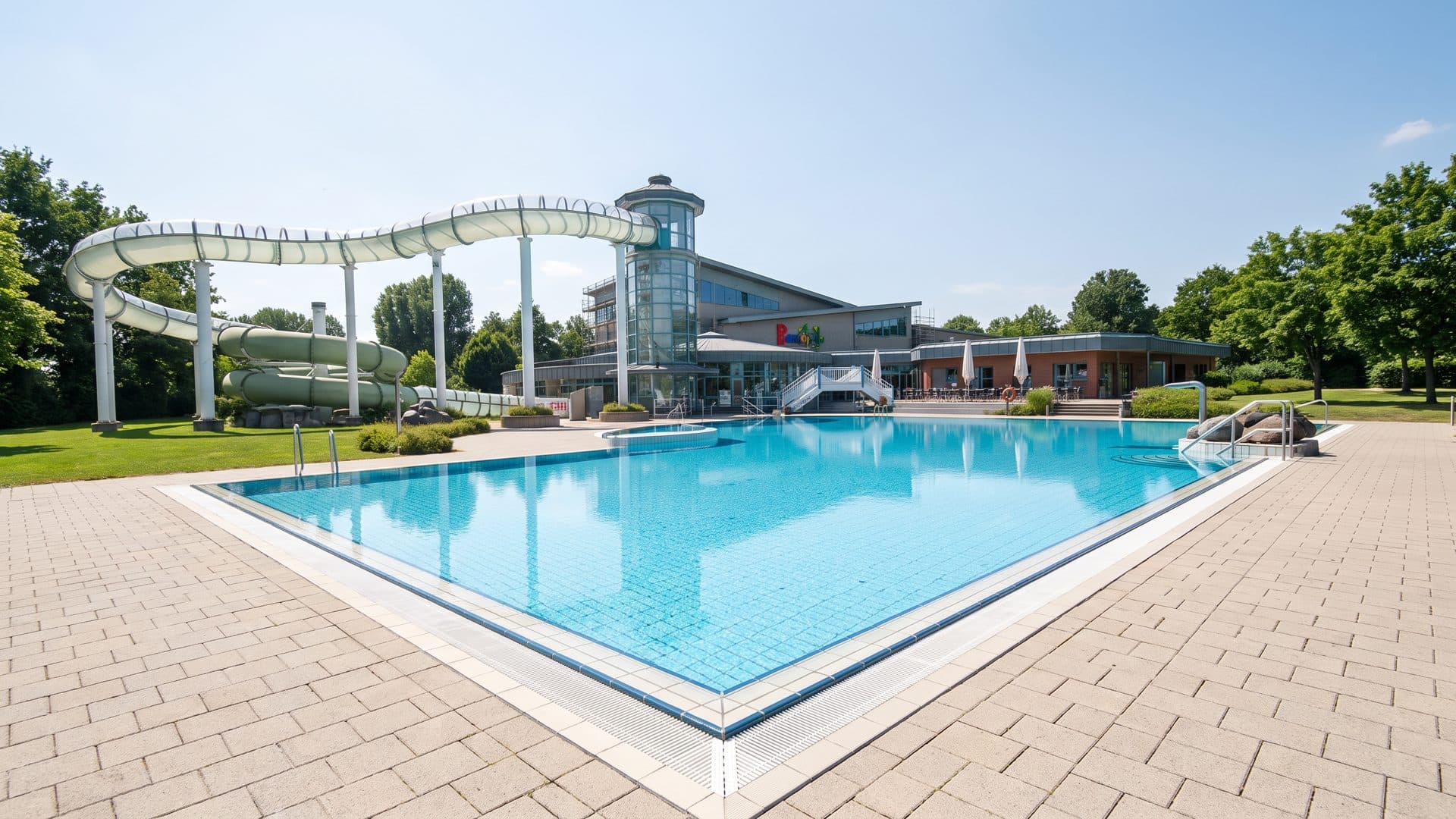 The outdoor pool of the Ronolulu below its white slide beside the bath building