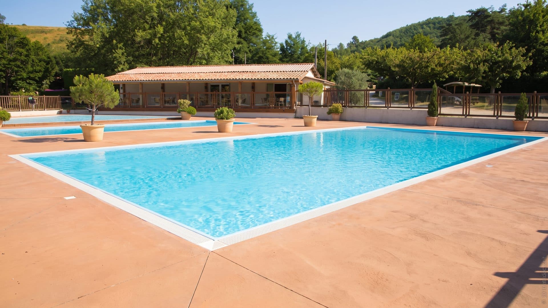 The outdoor pool of the Grande Garenne with its terracotta surround in front of the tiled pavilion