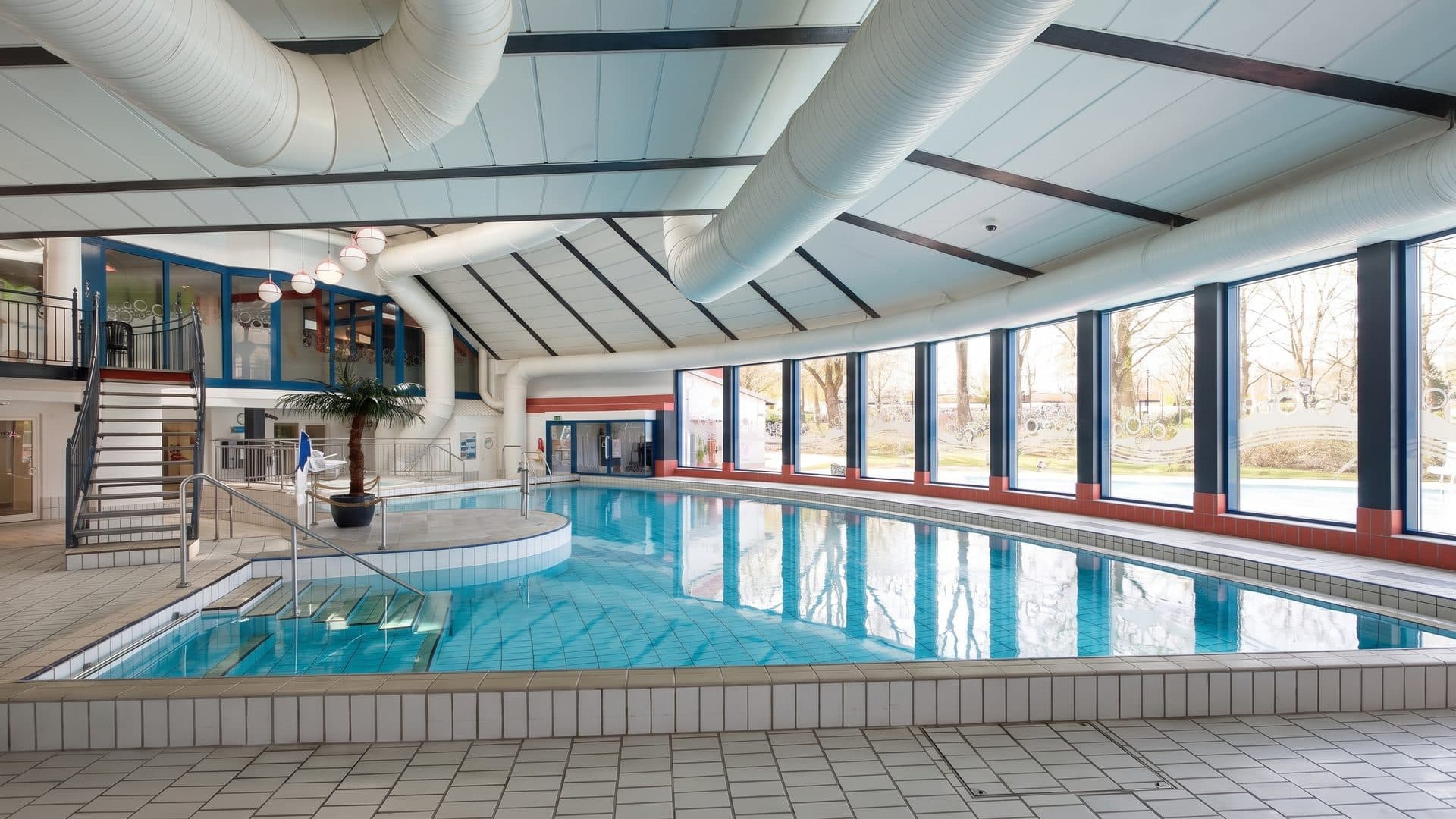 The indoor pool of the Heringhausen family baths running away under a curved white ceiling towards tall windows