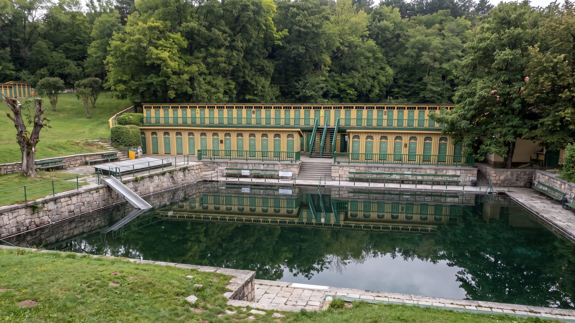 The arcaded historic bath house at Fischauer Thermalbad reflected in its open-air basin.
