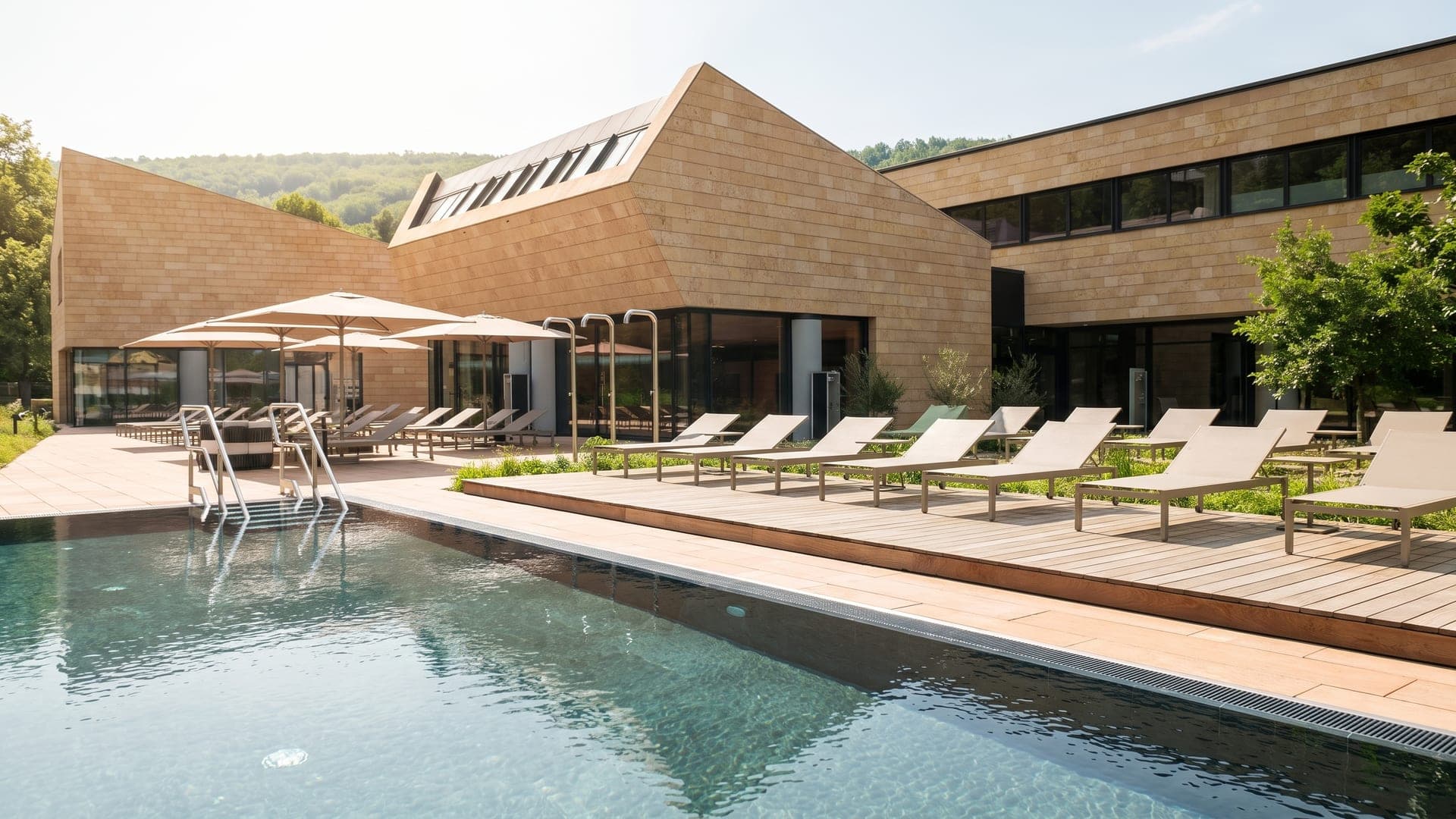 Outdoor pool beside the angular stone building, loungers along the deck