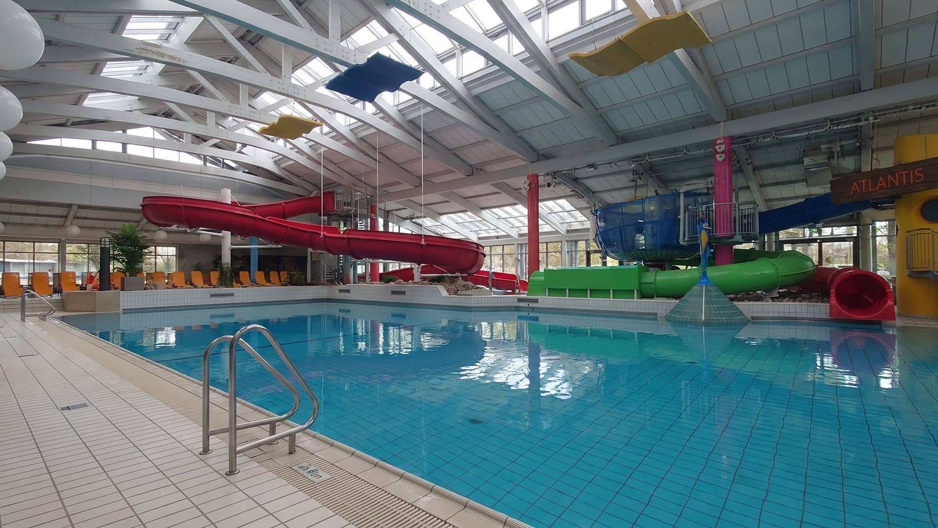 The pool hall of the Freizeitbad Atlantis, with its red water slide and glazed roof above the water