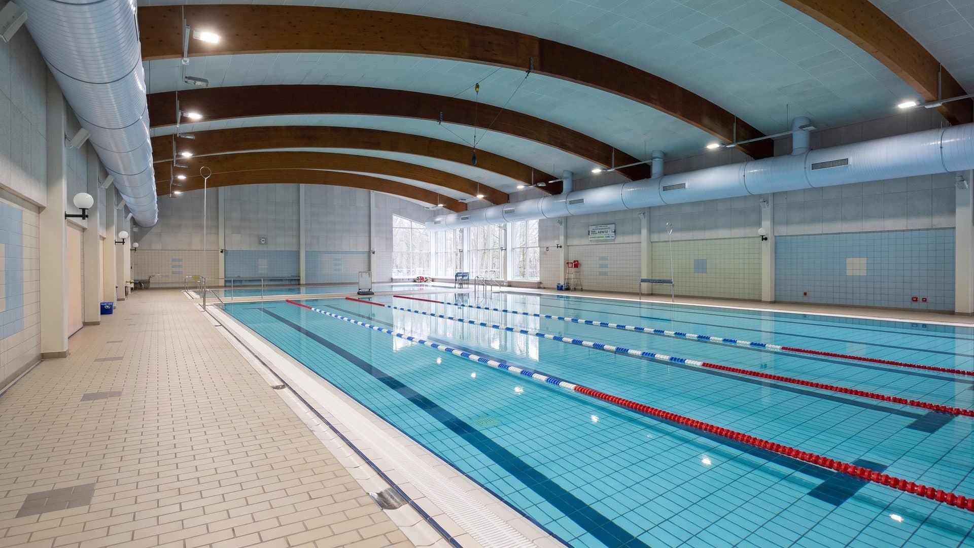 The lane pool of Freizeitbad De Buett running away under its arched timber roof