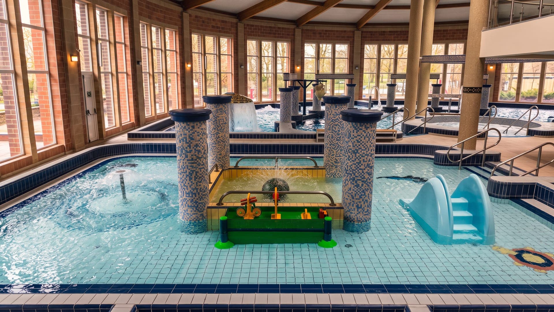 Indoor pool with tiled columns and a children's play structure