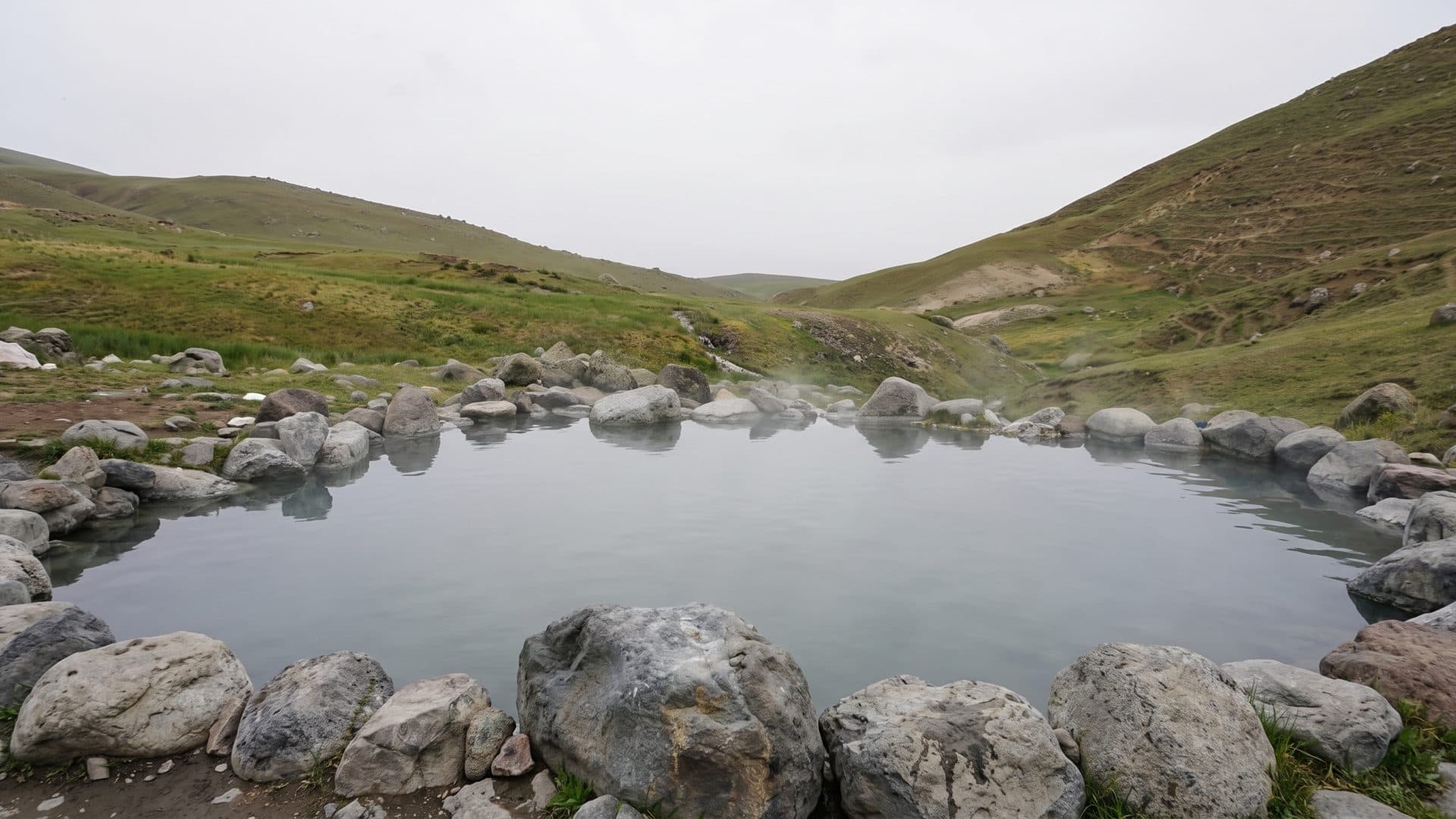 The rock-lined thermal pool at Gavmish Goli near Sarein, set in the grassy hillside