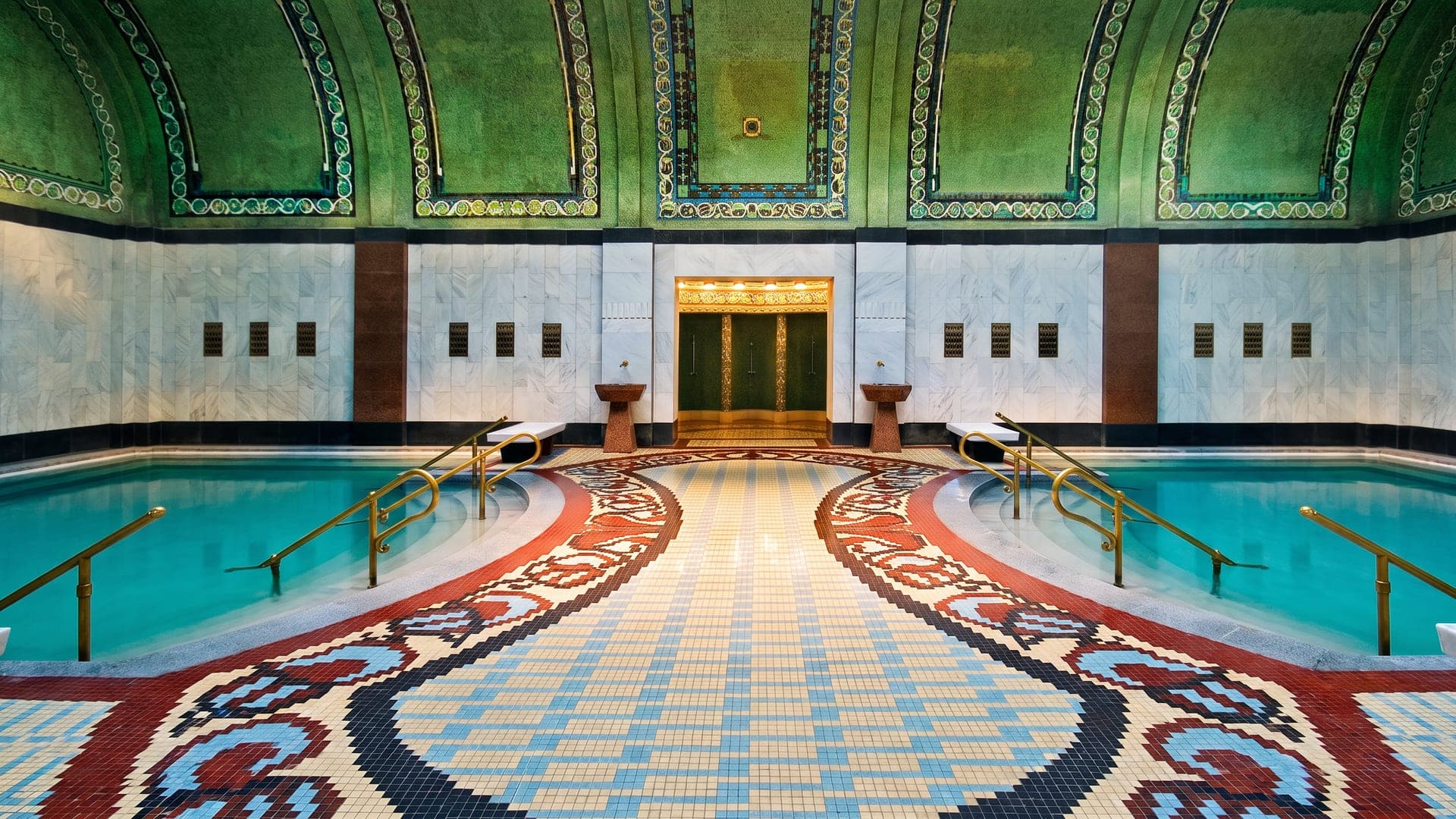 Art nouveau bathing hall with green tilework and a patterned mosaic floor