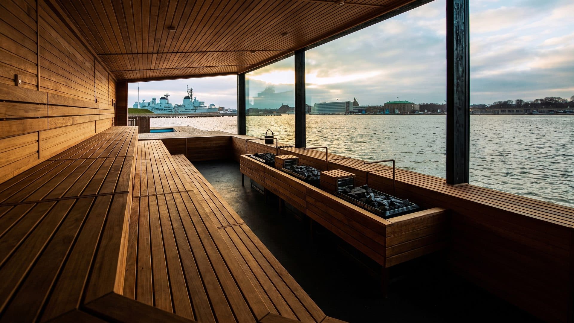 The timber sauna of Glaecier with its benches along the panoramic window over the water