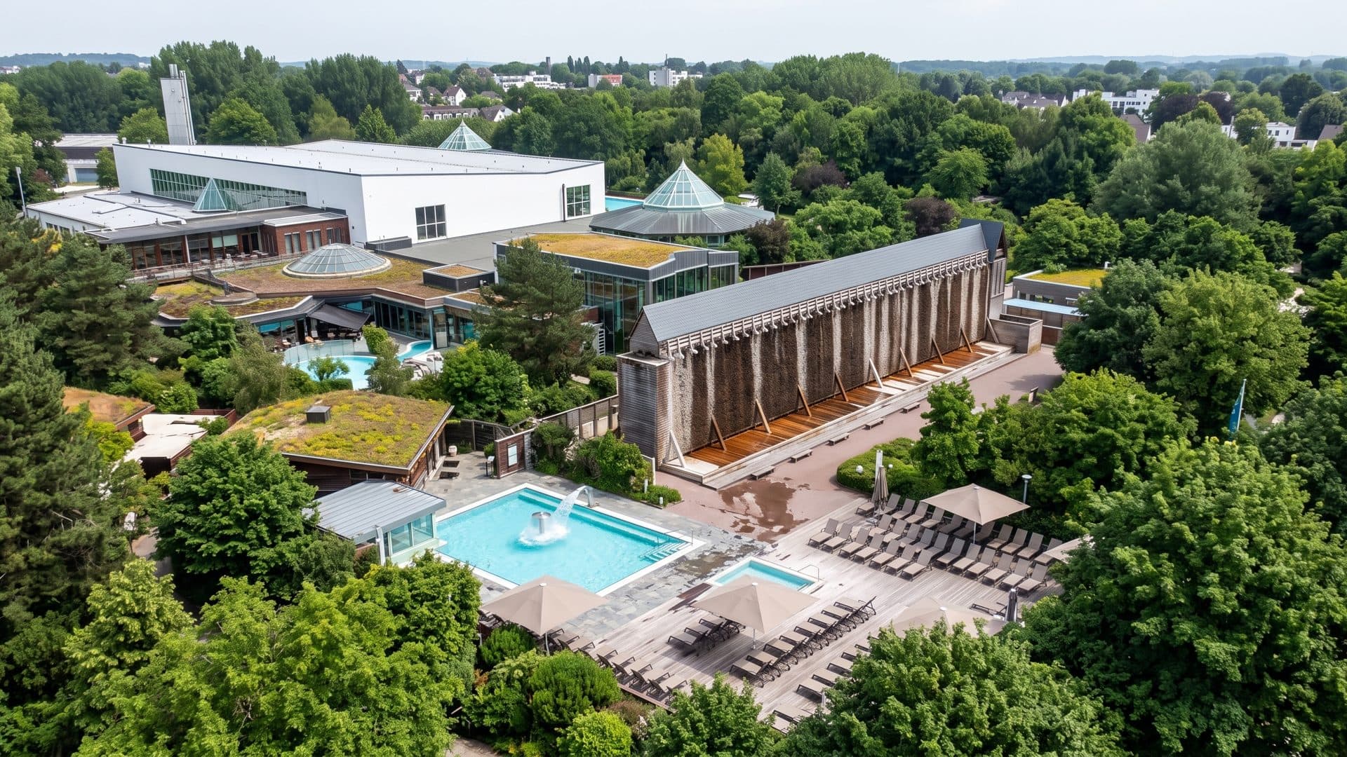 The baths from the air: the pavilions of the sauna garden, the colonnade and the outdoor pool among the trees.