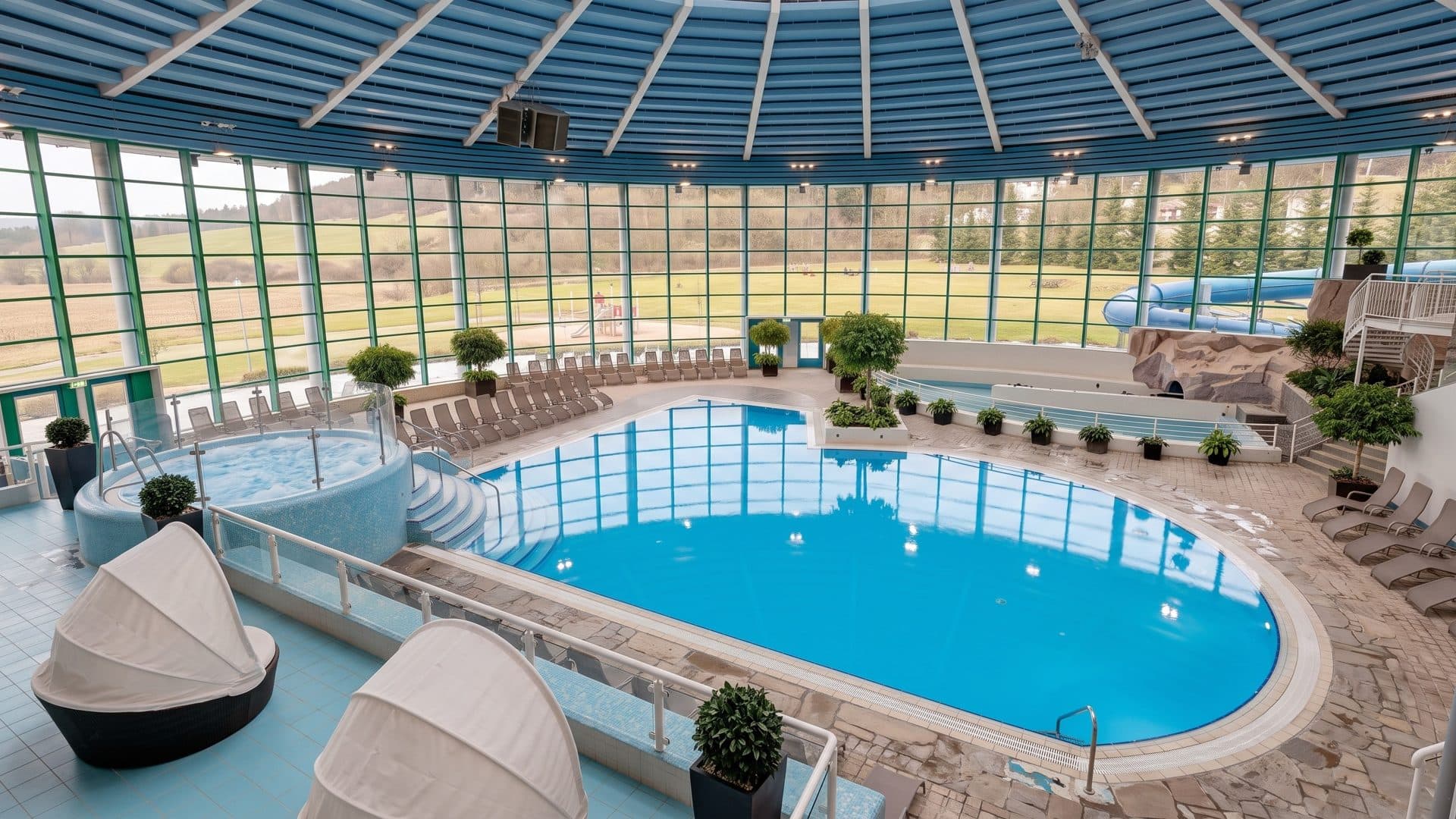 The indoor leisure pool of H2Oberhof with canopied loungers under a round glazed roof