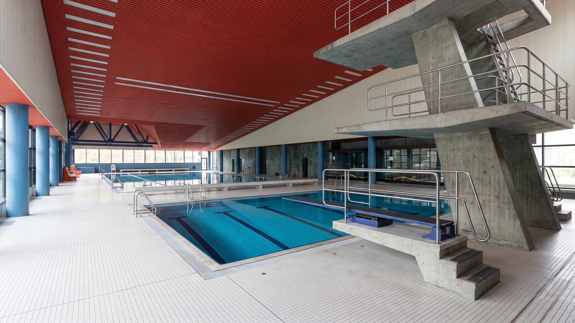 The indoor pool of the Hallenfreizeitbad with its diving platforms under a red ceiling