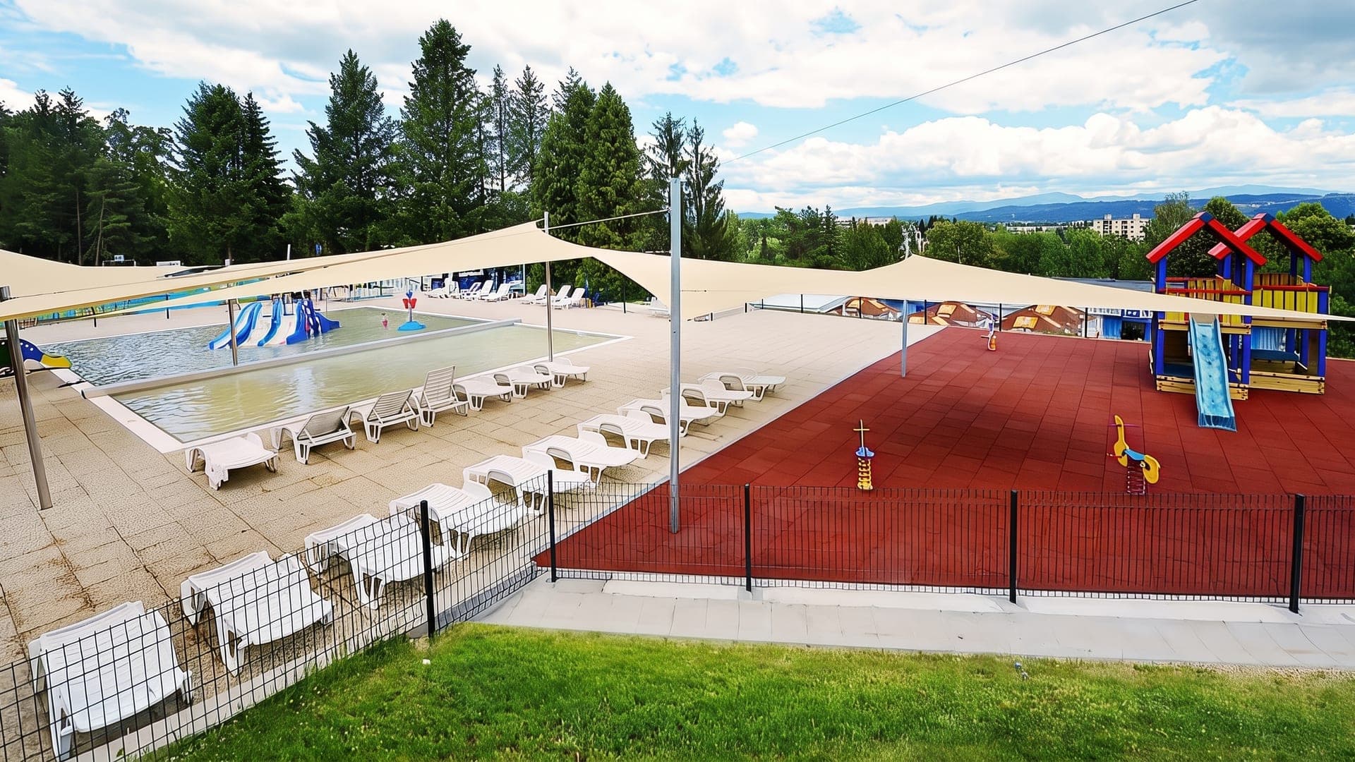 Outdoor pool under white shade sails, with a children's play area alongside