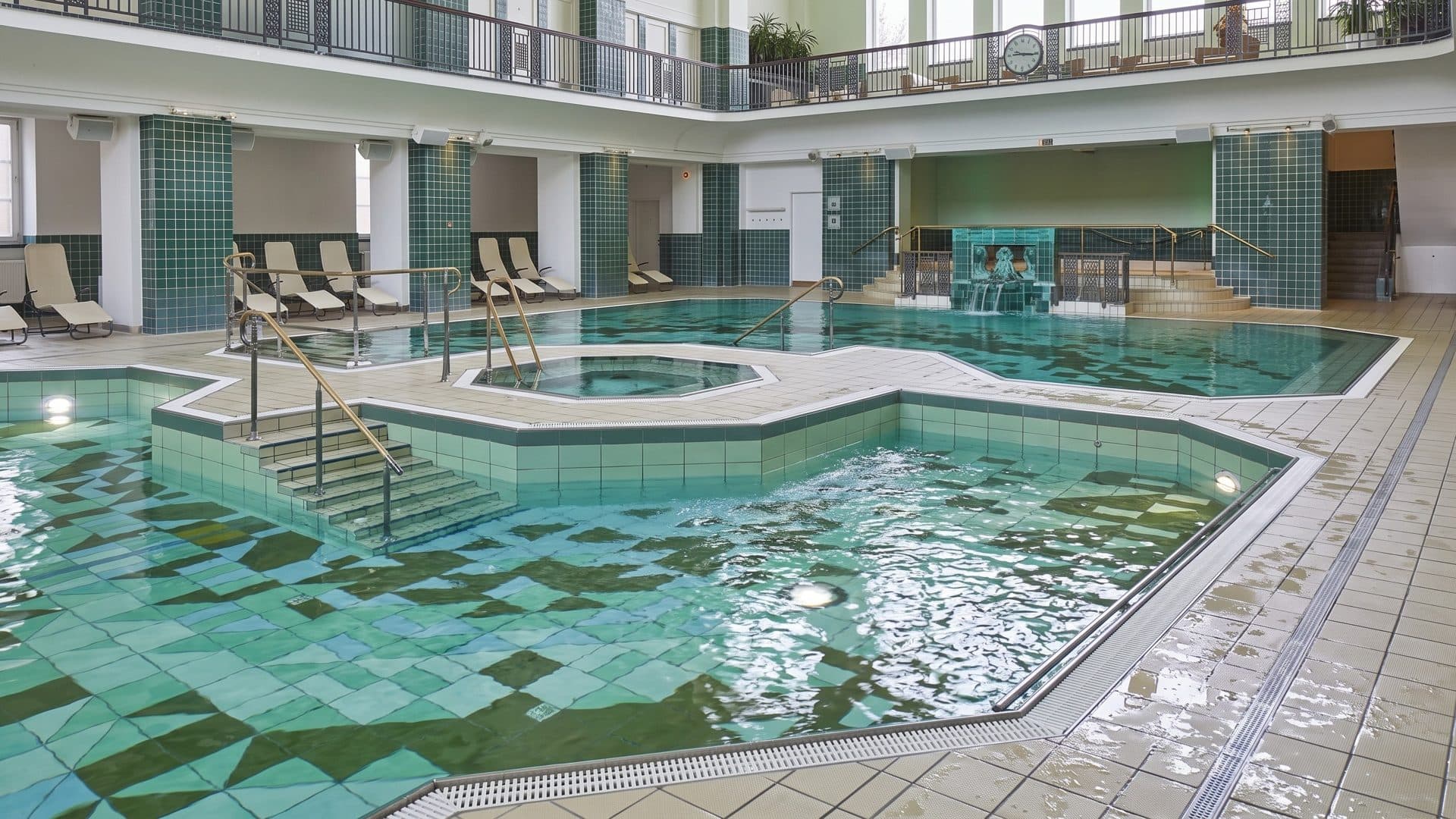 The green-tiled pool of the Holthusenbad with its angular outline, a round whirlpool in the middle and loungers along the gallery